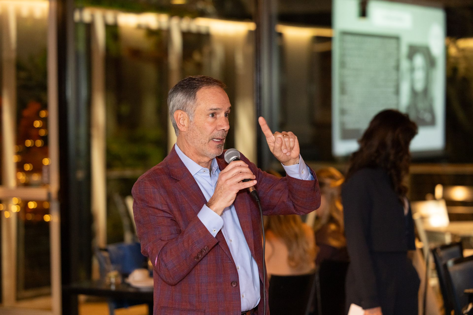 A man in a suit is speaking into a microphone.
