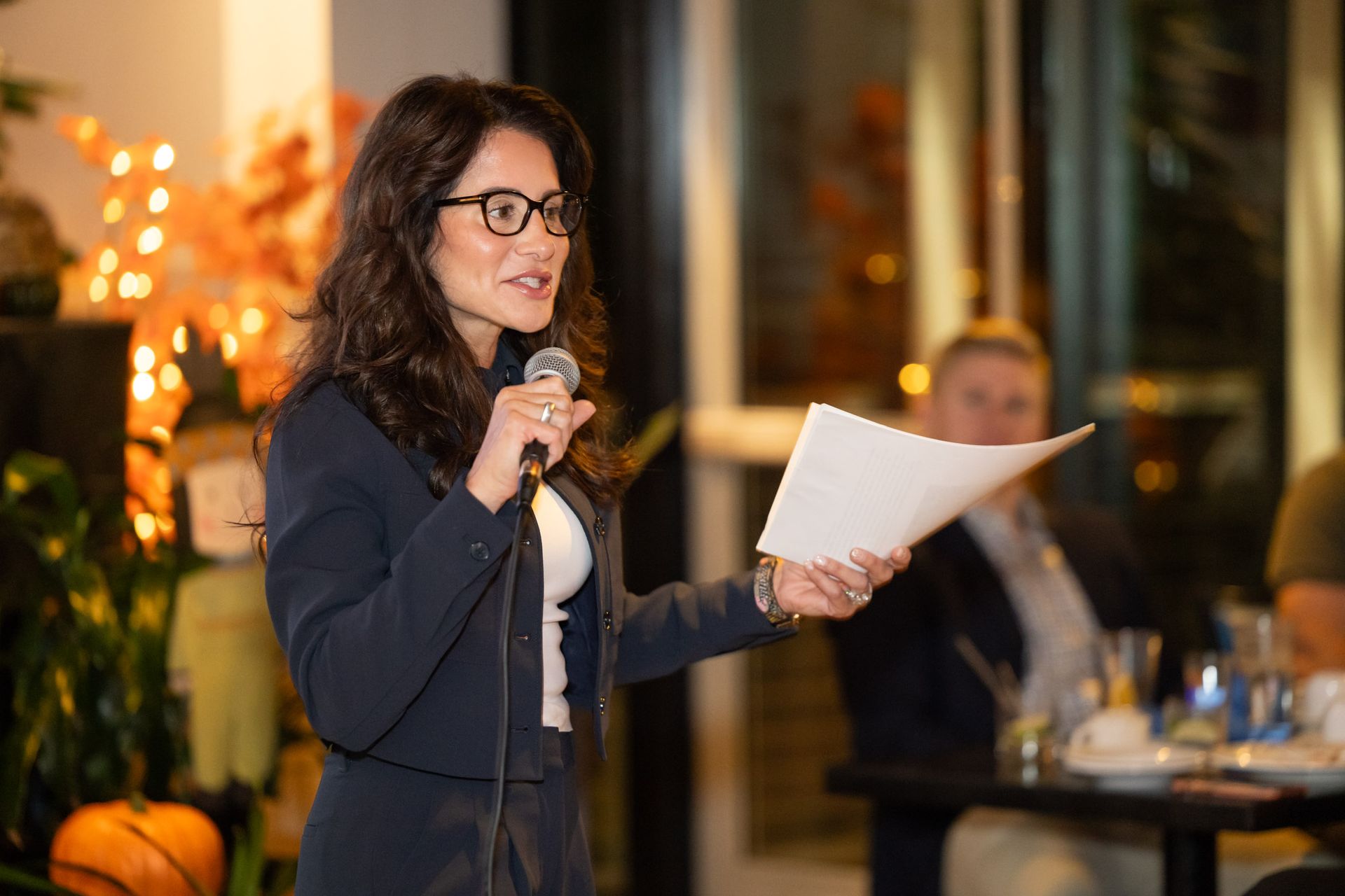 A woman is holding a piece of paper and speaking into a microphone.