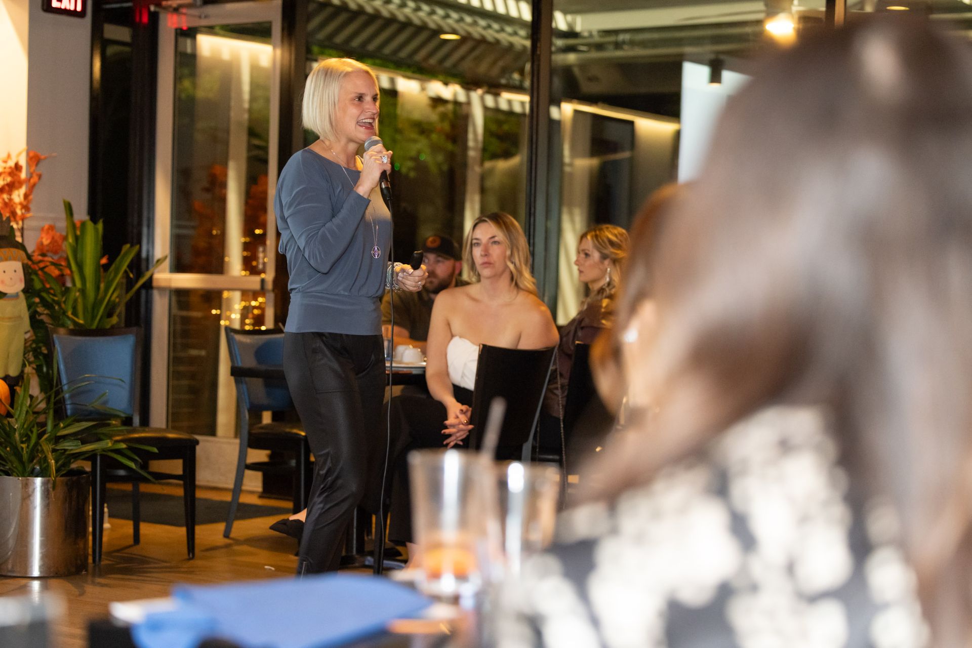 A woman is standing in front of a group of people holding a microphone.