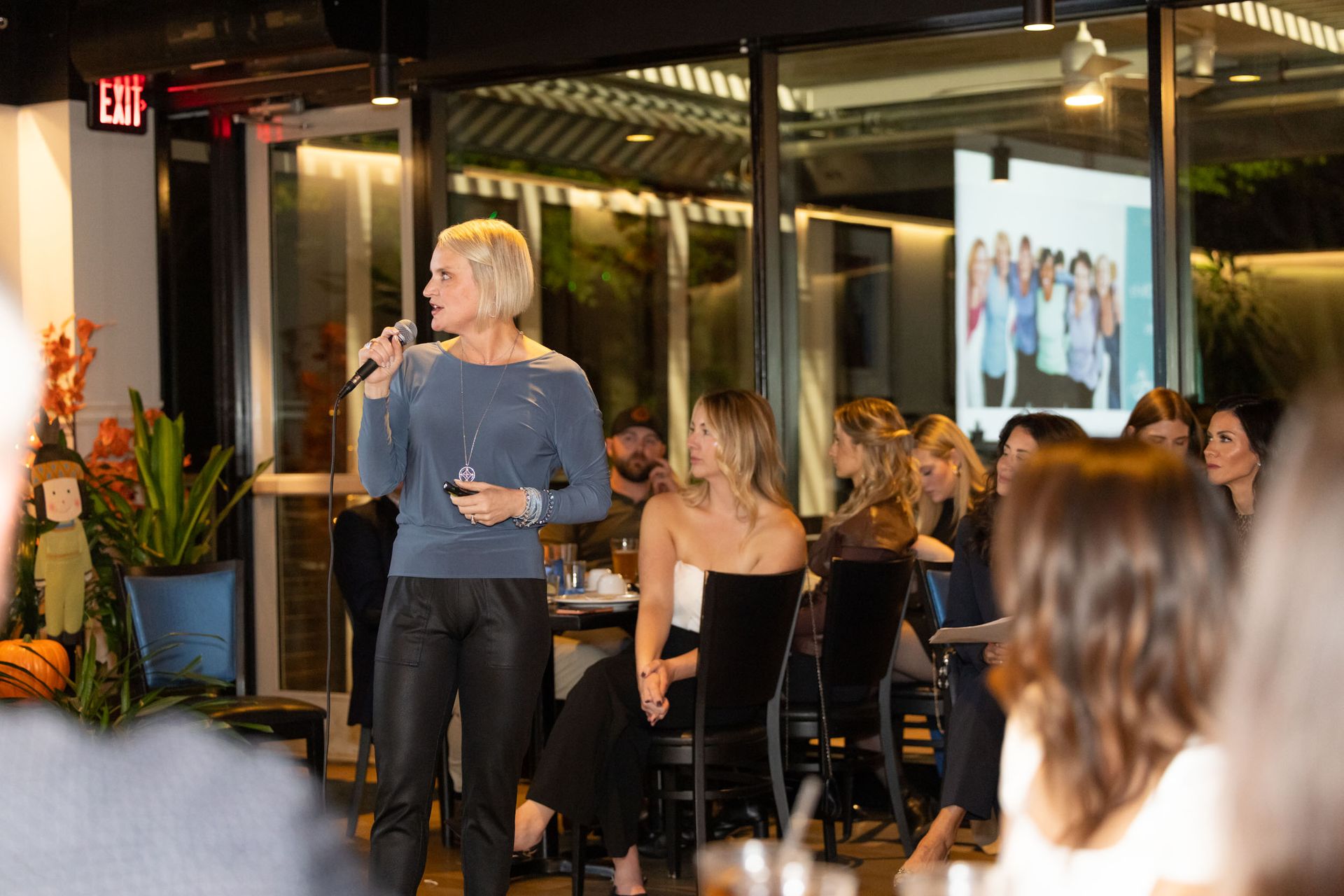 A woman is giving a presentation to a group of people in a restaurant.