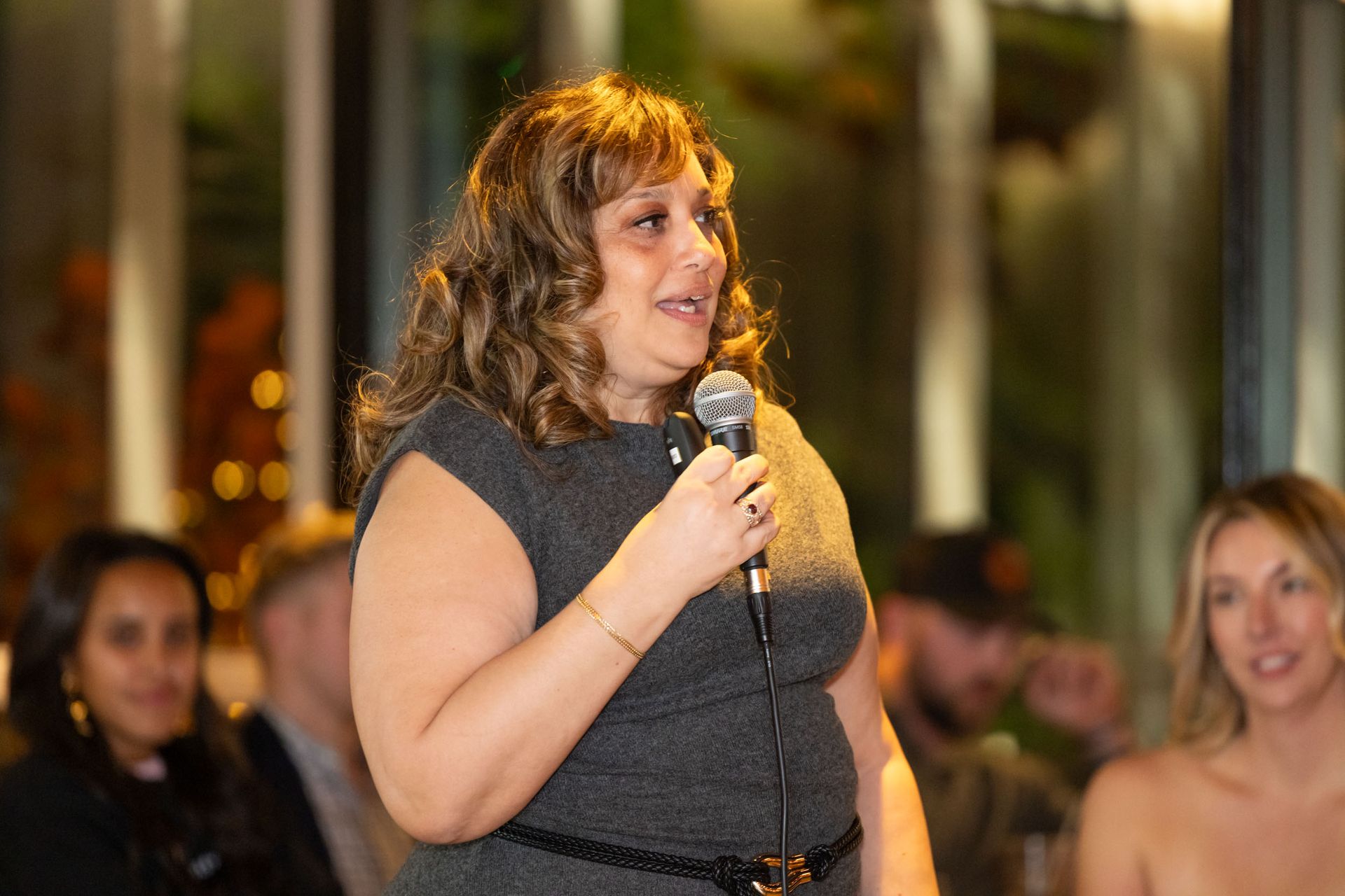 A woman is holding a microphone in front of a crowd of people.