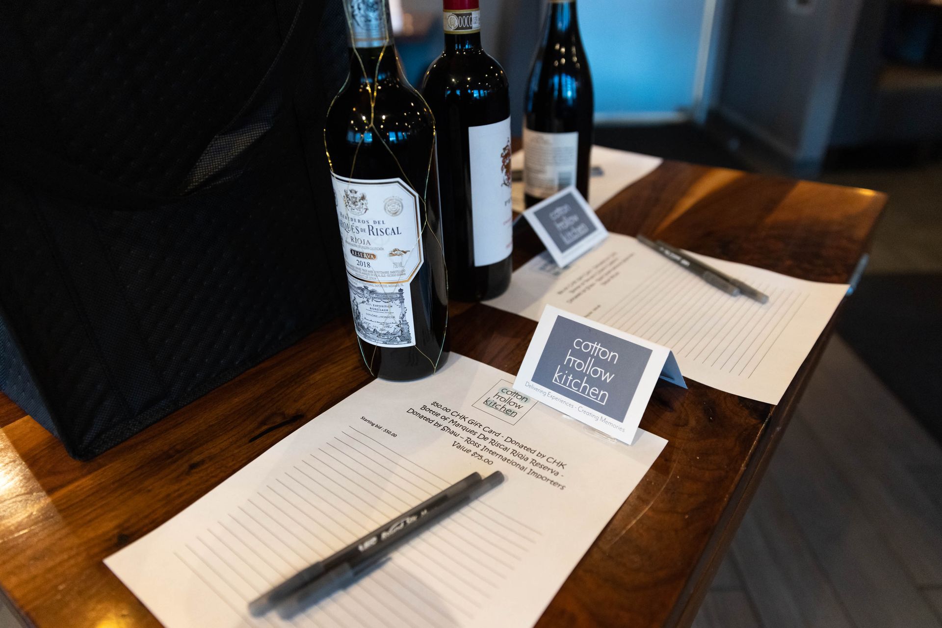 A table with bottles of wine and papers on it