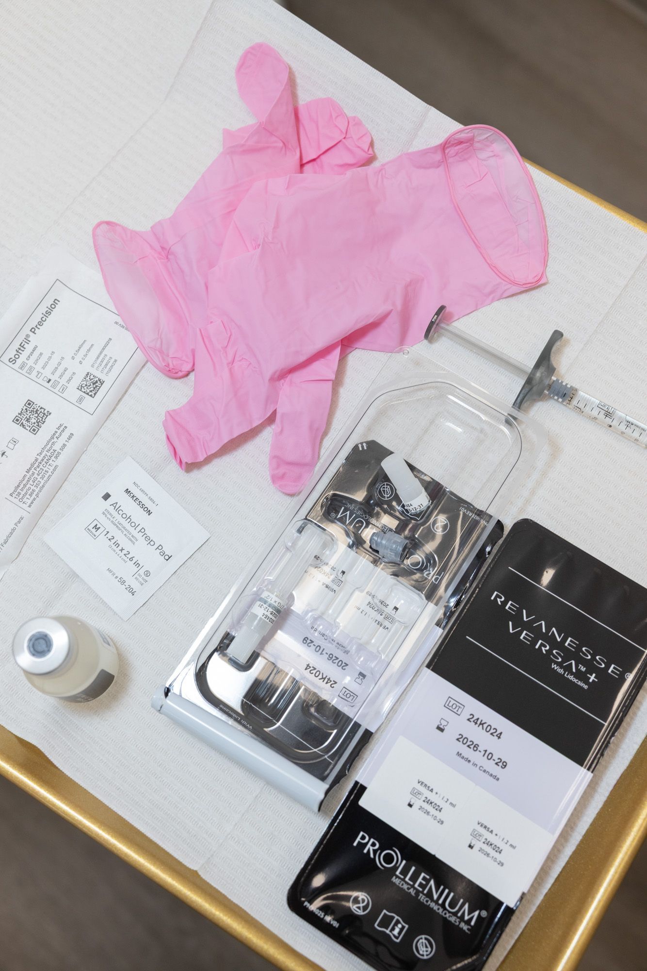 Pink medical gloves and syringes on a tray, prepared for a procedure with various medical vials and packaging.