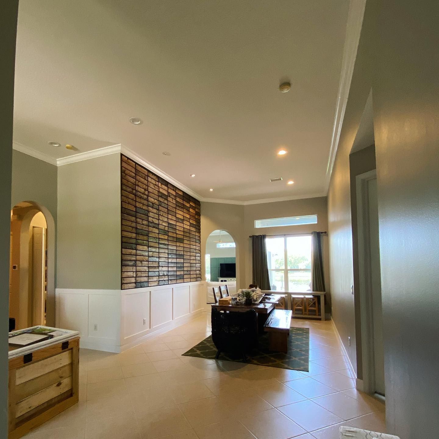 Spacious modern dining room with white walls, wood accents, a long table, and large windows.