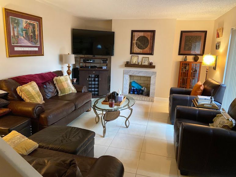 Cozy living room with leather sofas, TV, fireplace, coffee table, and framed wall art.