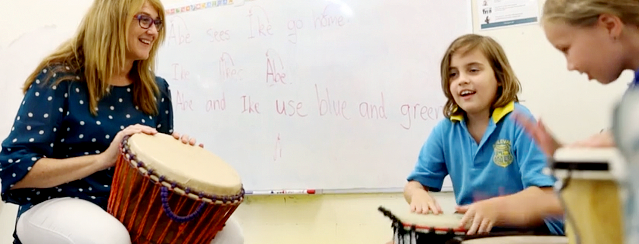Music teacher helping children play drums in a classroom