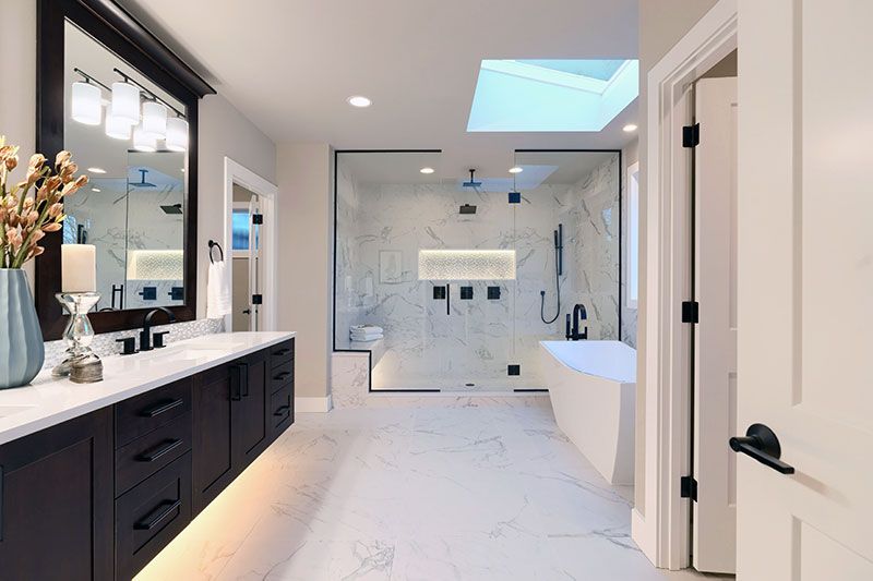 Luxury modern home bathroom interior with dark brown cabinets, white marble, walk in shower, free standing tub. 