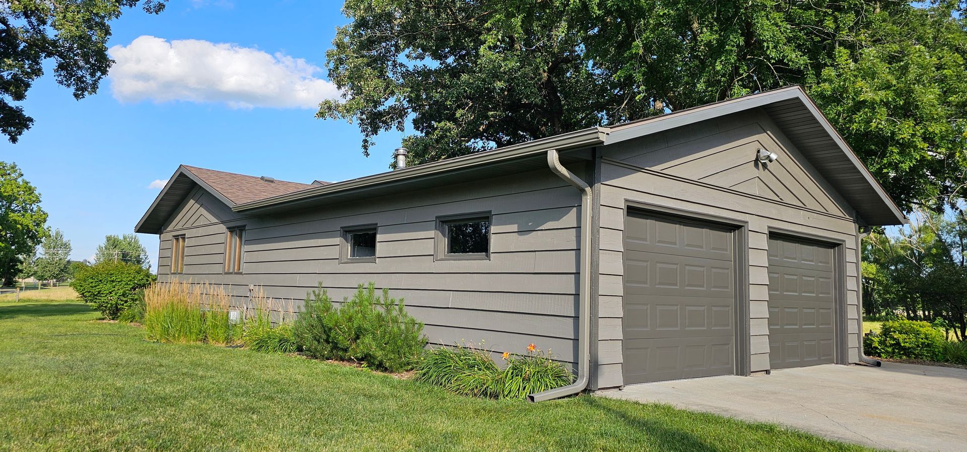 A large house with two garages and a sunset in the background.