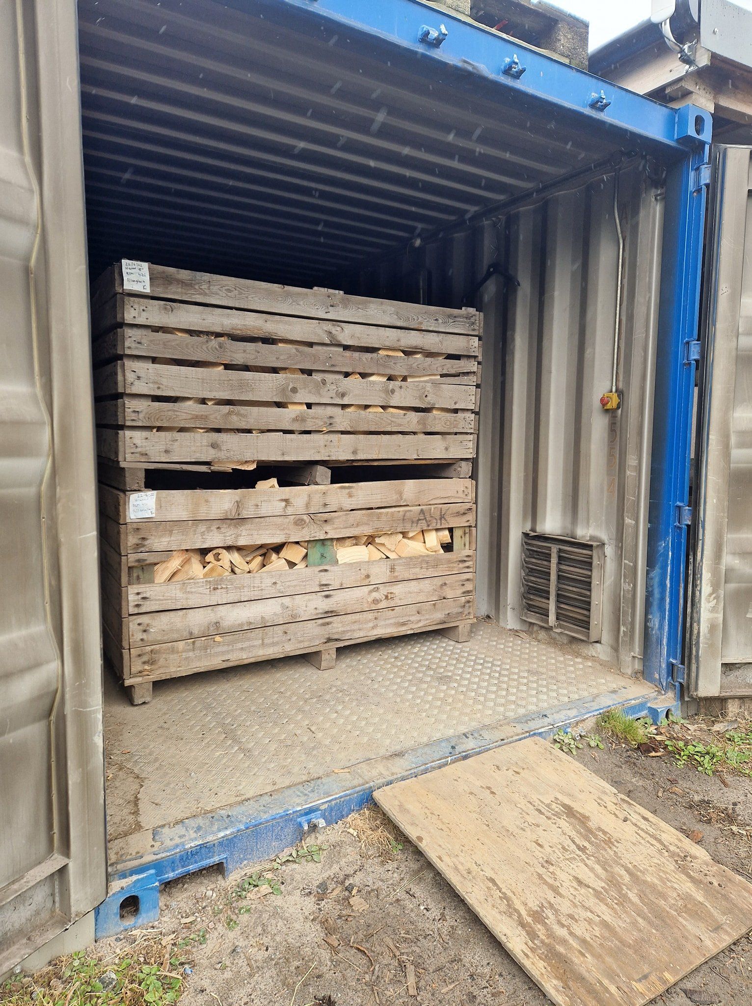 A large wooden crate is sitting inside of a shipping container.