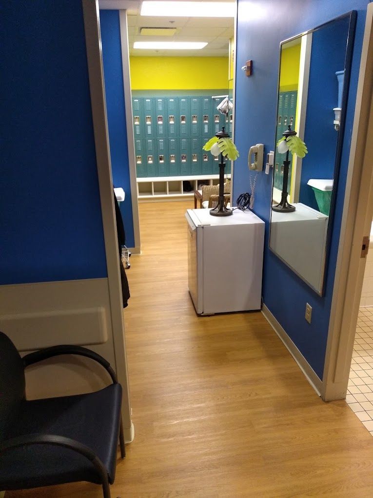 A hallway with lockers and a chair and a mirror