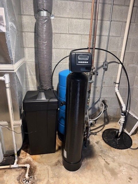 Black water filter control head with digital display and hoses mounted on a tank top.