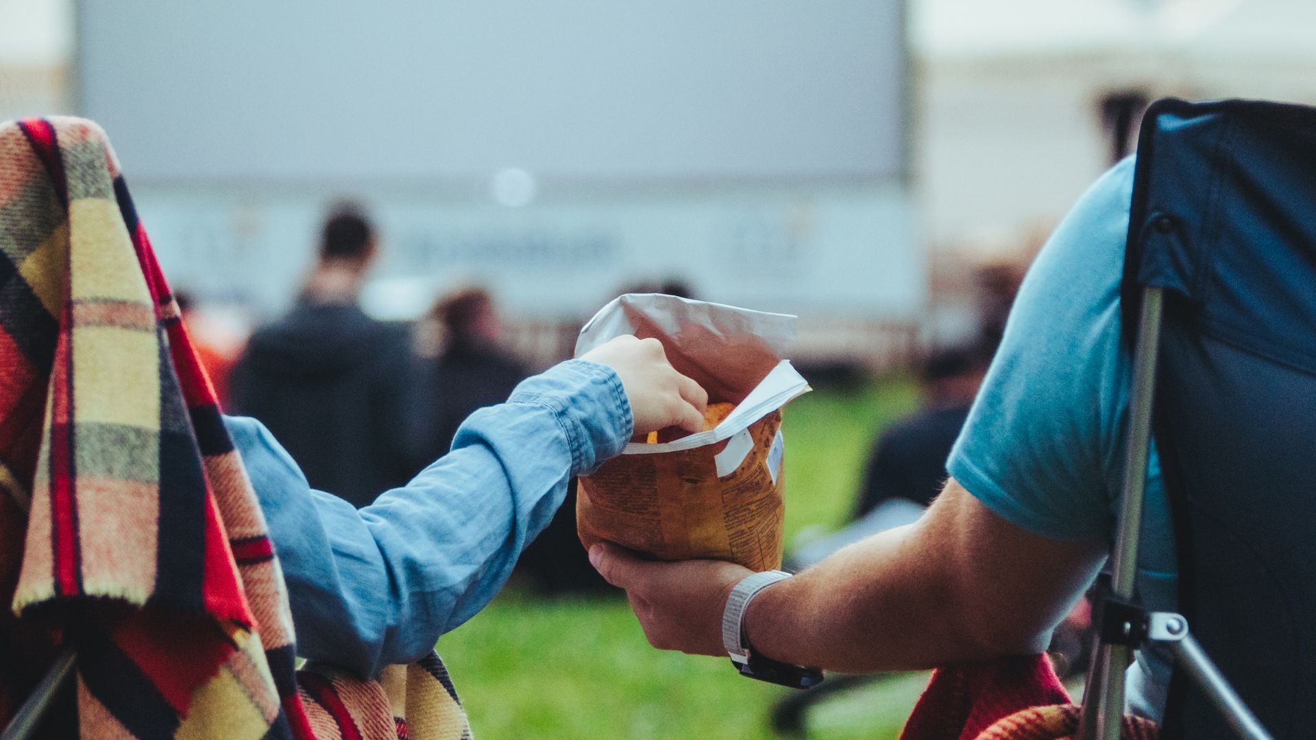 two people sharing a bag of chips at an outdoor movie theater