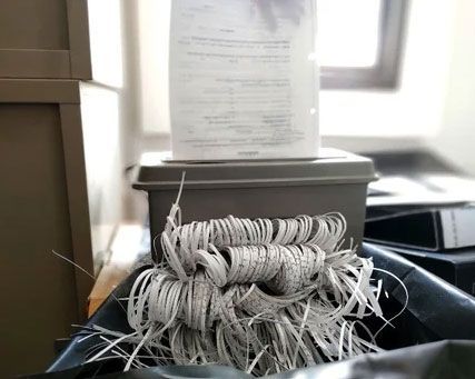 Tangled white cord on a desk in front of a gray box near a window