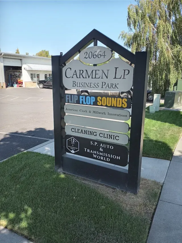 A black directory sign for Carmen LP Business Park listing several businesses, set against a sunny, outdoor background | SP Auto and Transmission World