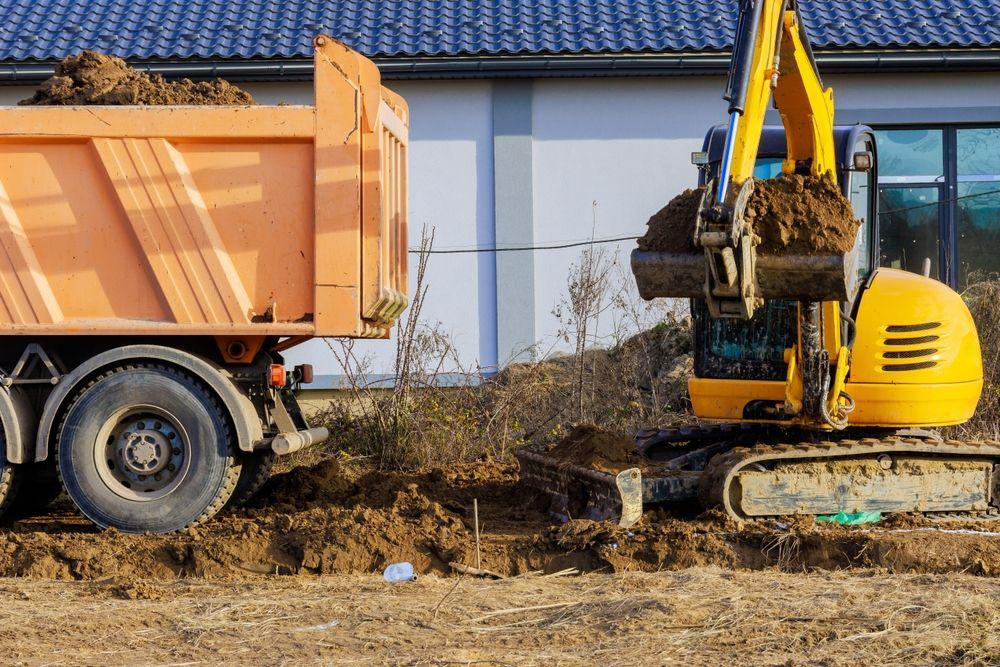 Excavator loading dirt into an orange dump truck at a construction site