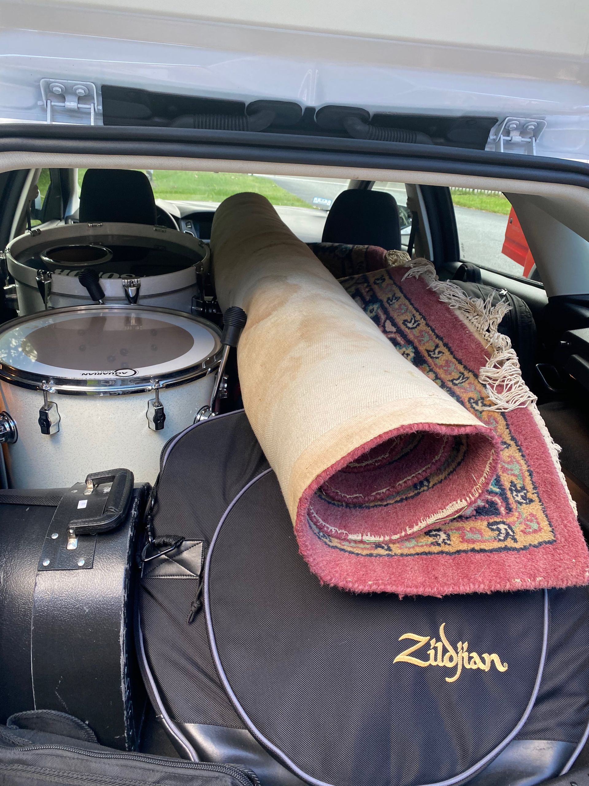 a rolled rug on a drum set in the back of the car