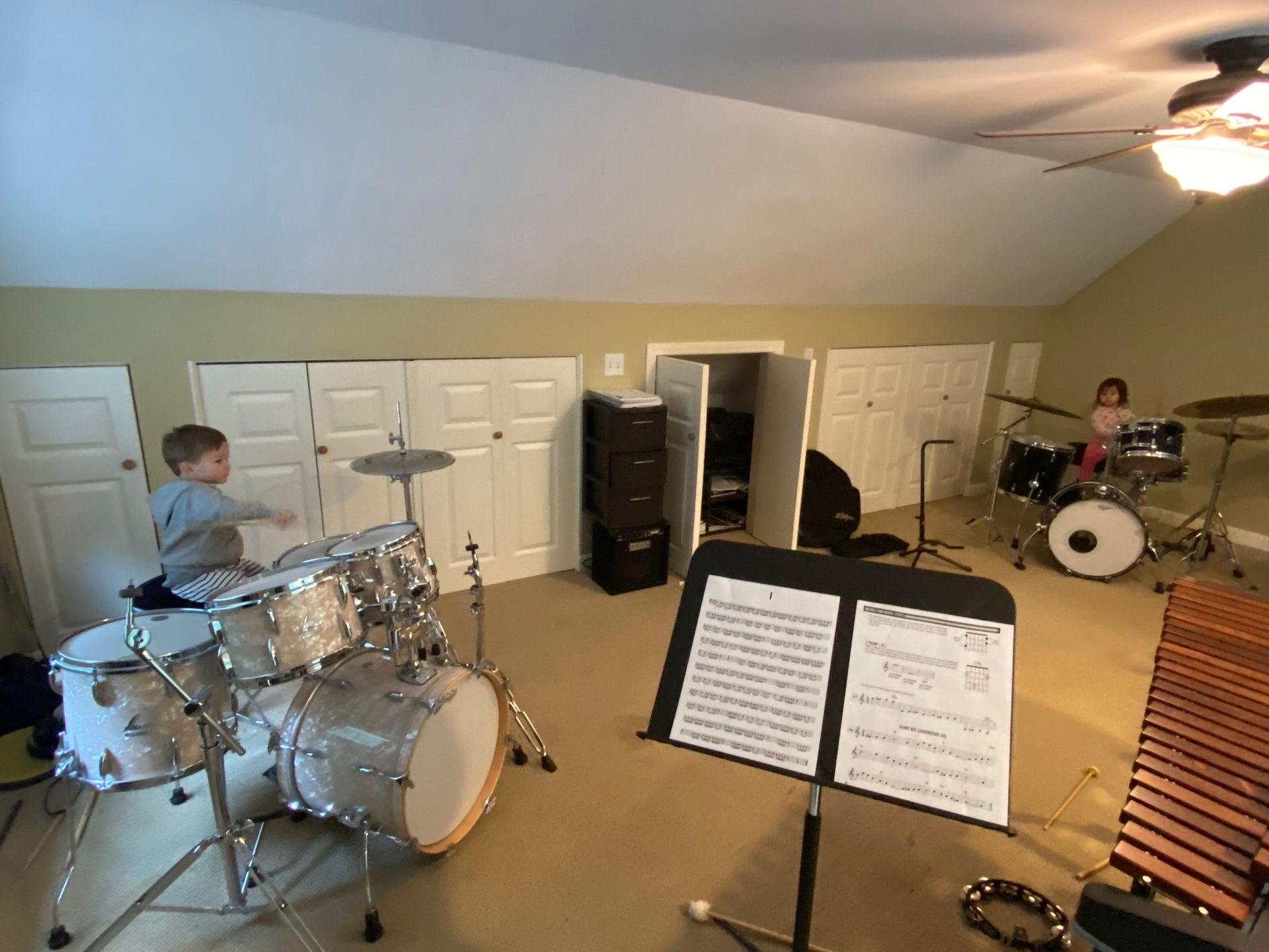 two kids on a drum set in a practice room