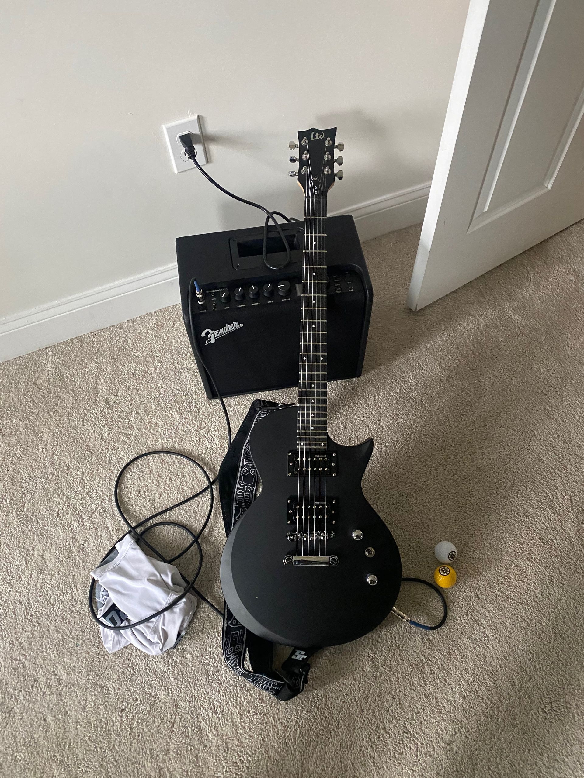 a black electric guitar and an amplifier
