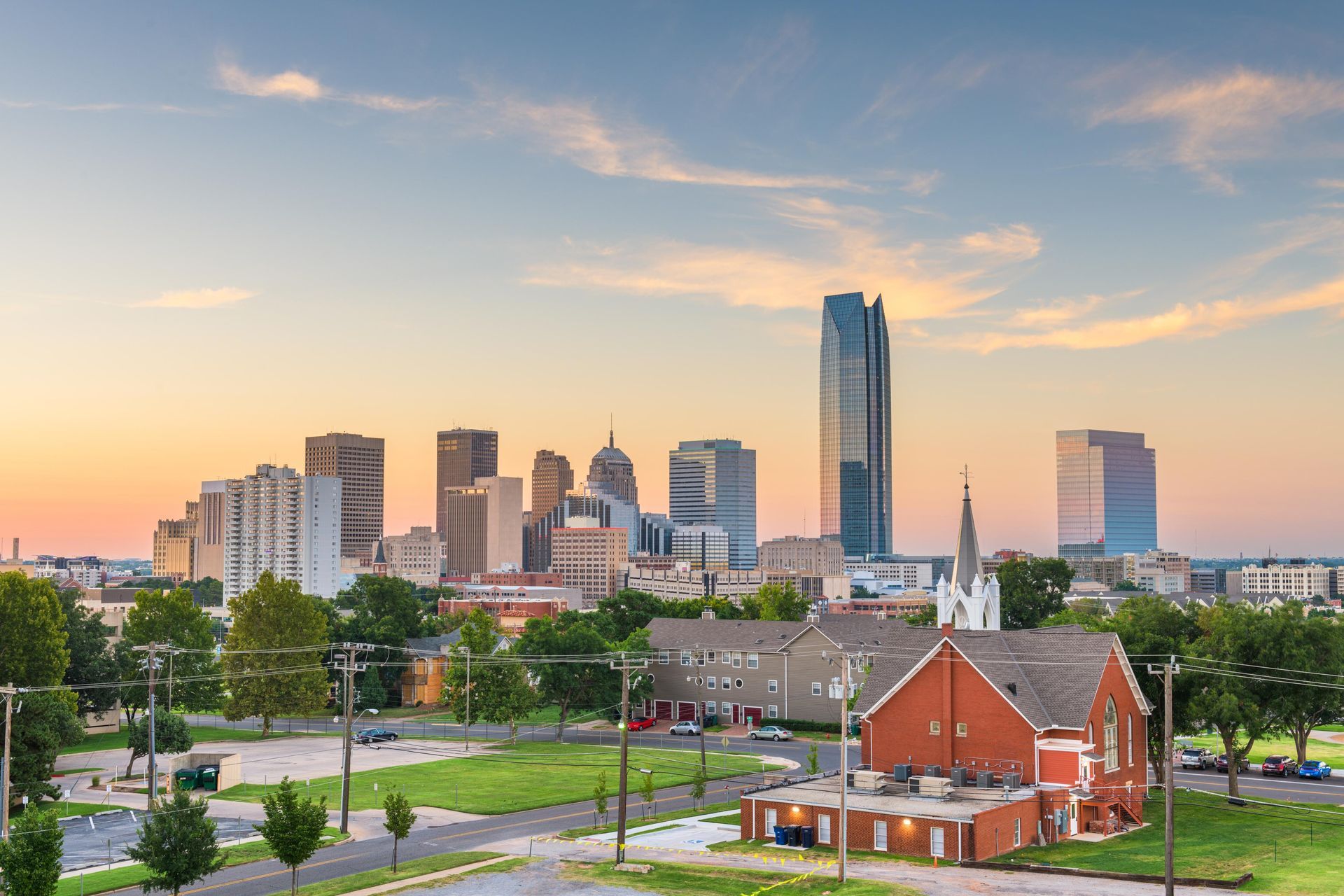 City skyline at sunset with a red brick building and green park in the foreground