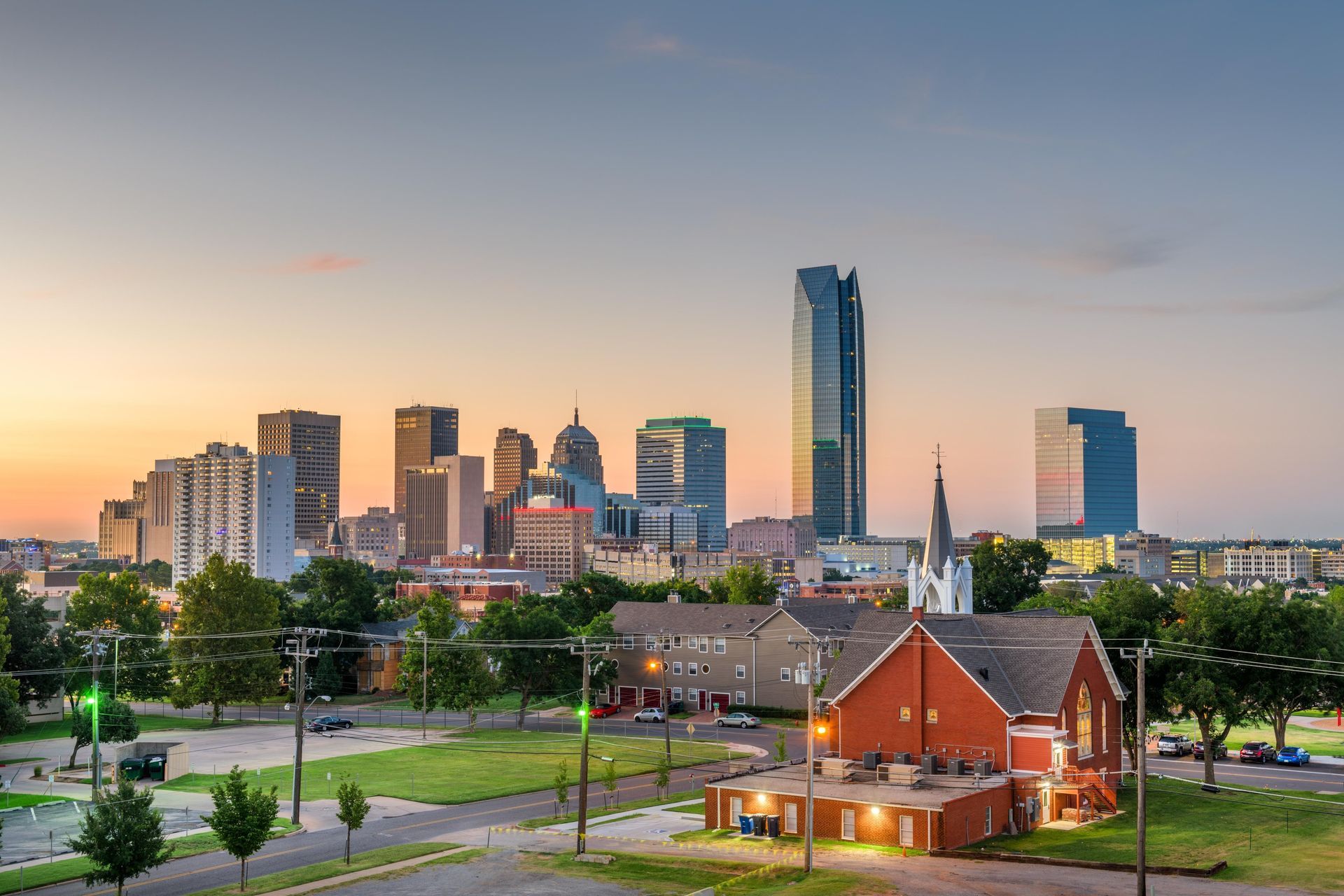 City skyline at sunset with a church in the foreground and a park beside it