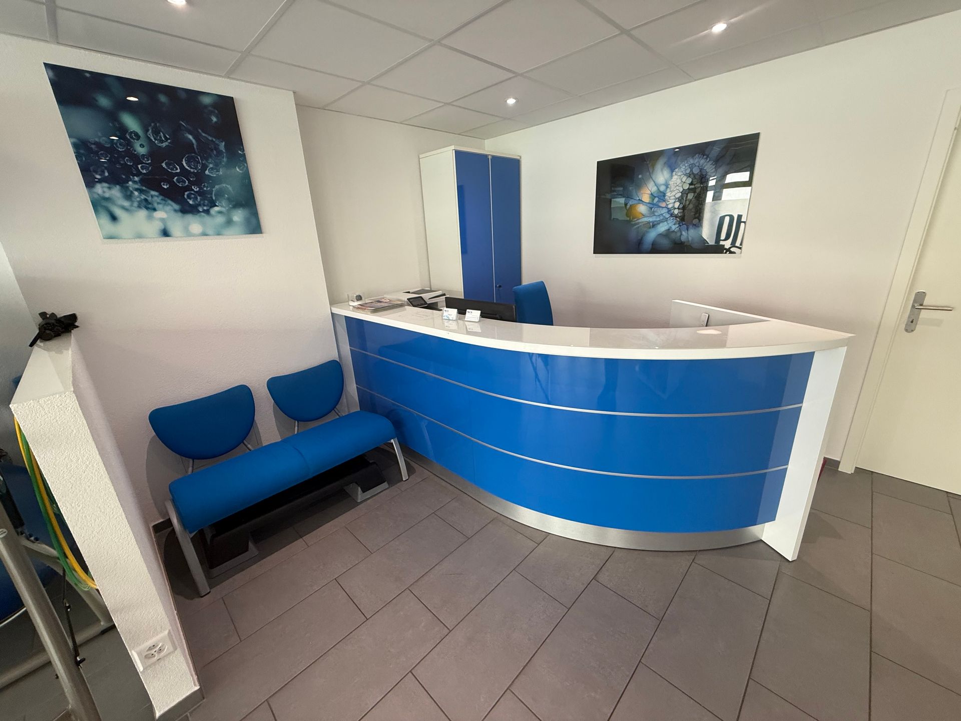 Réception avec chaises bleues dans un petit hall d'immeuble de bureaux blanc