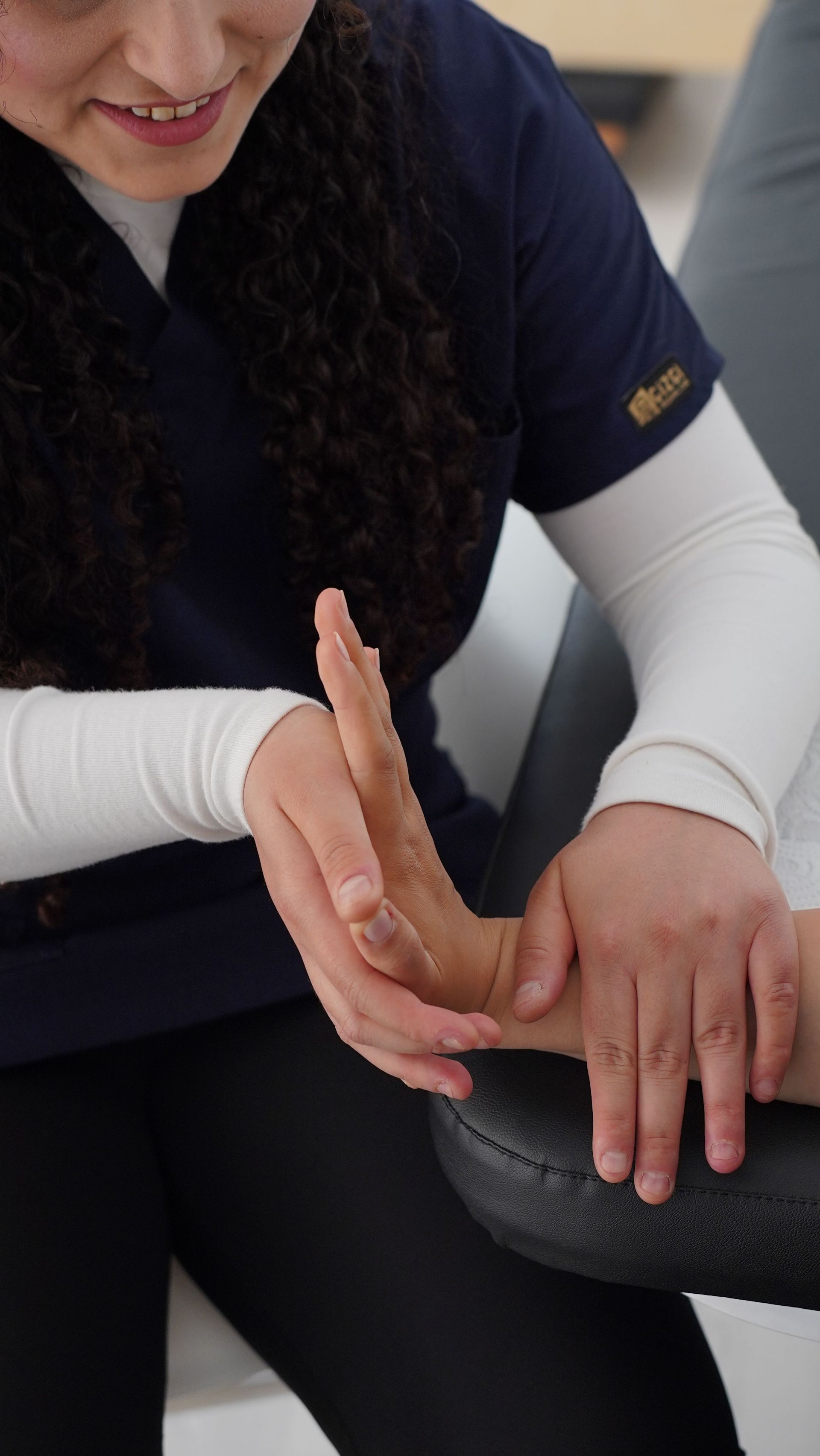 Une personne effectue une démonstration de massage des mains sur la main d'une autre personne dans un contexte thérapeutique.