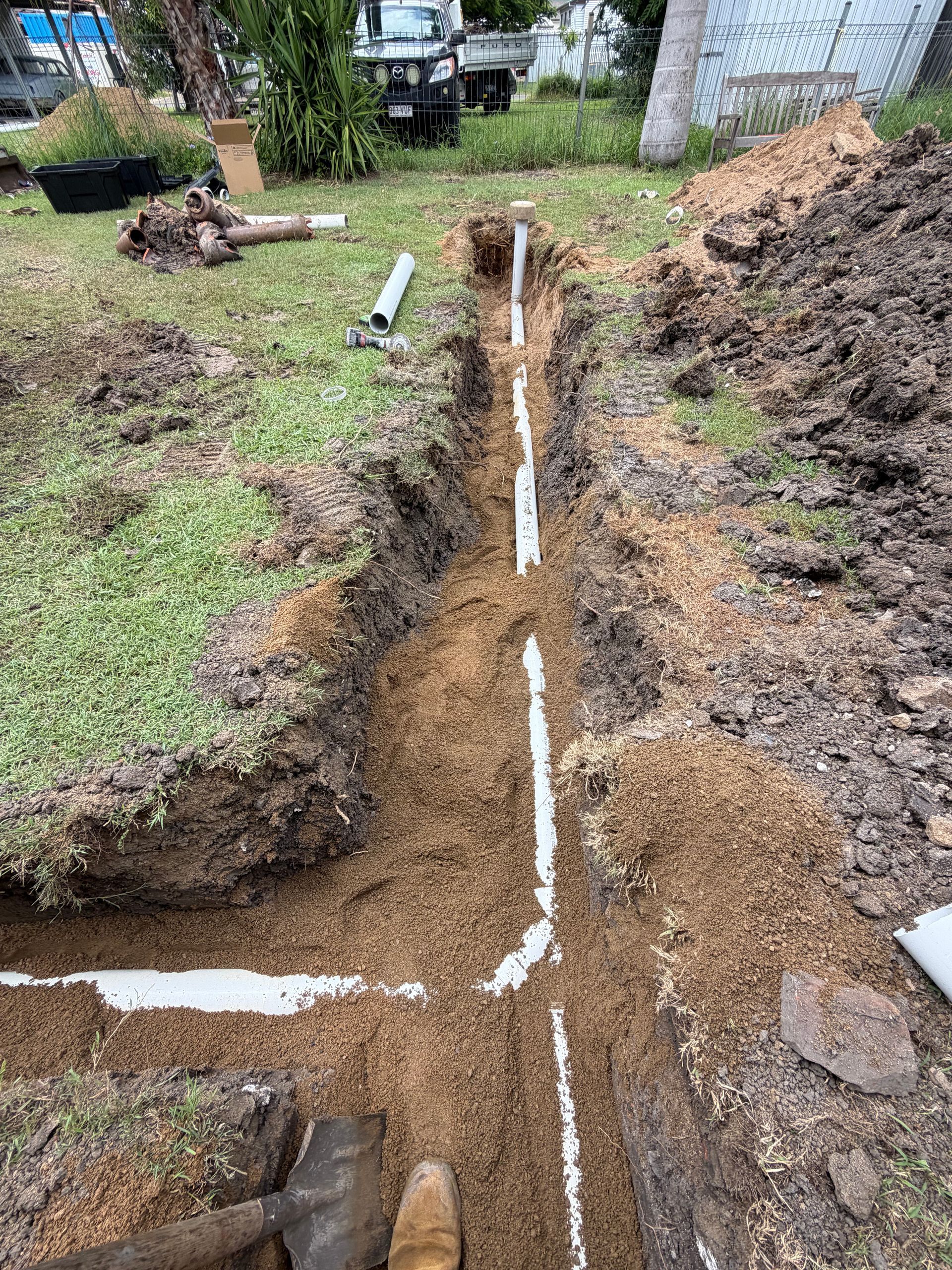Trenched yard with white PVC pipe laid in a narrow dirt trench — Truflow Plumbing & Gas Solutions in Rockhampton City, QLD