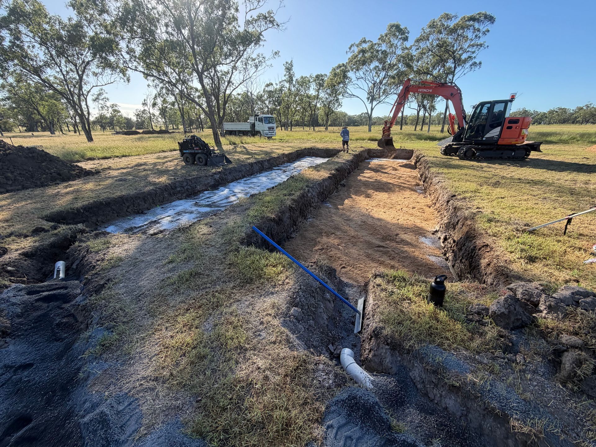 Construction trench beside a rural road with workers — Truflow Plumbing & Gas Solutions in Rockhampton City, QLD