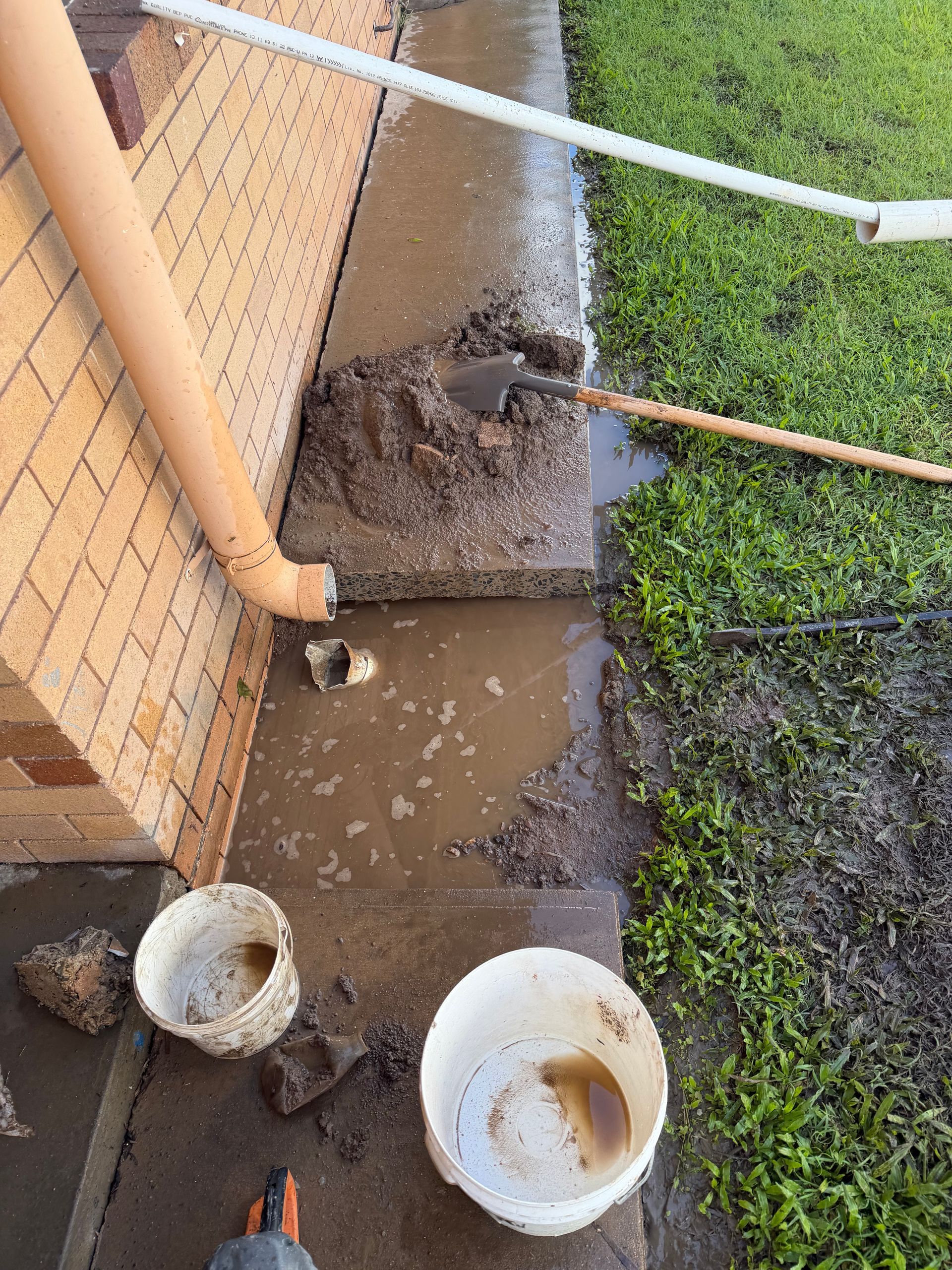 Flooded muddy patio beside brick wall and orange pipe — Truflow Plumbing & Gas Solutions in Rockhampton City, QLD