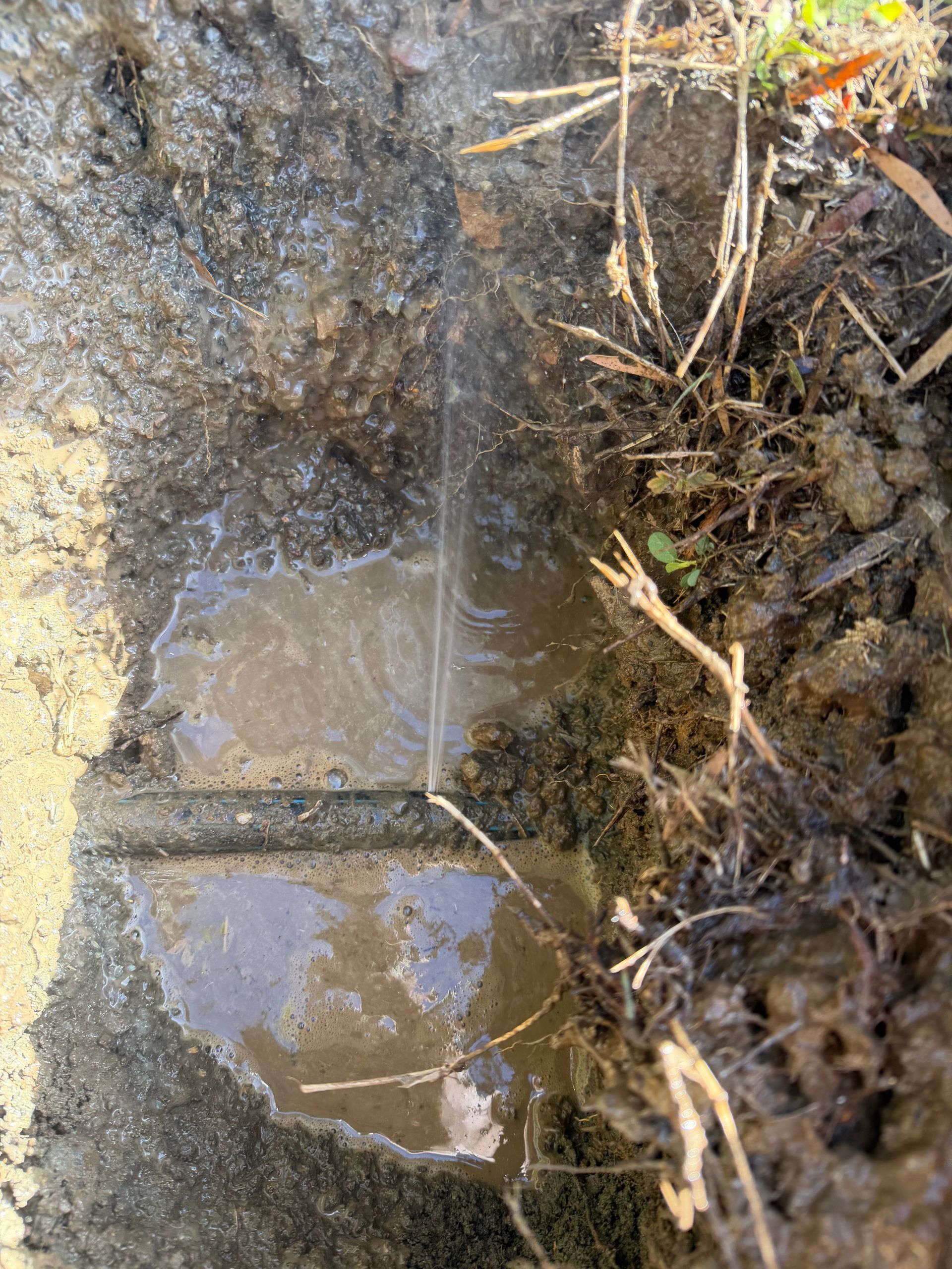 Muddy trench with a small puddle of water and wet soil around it— Truflow Plumbing & Gas Solutions in Rockhampton City, QLD