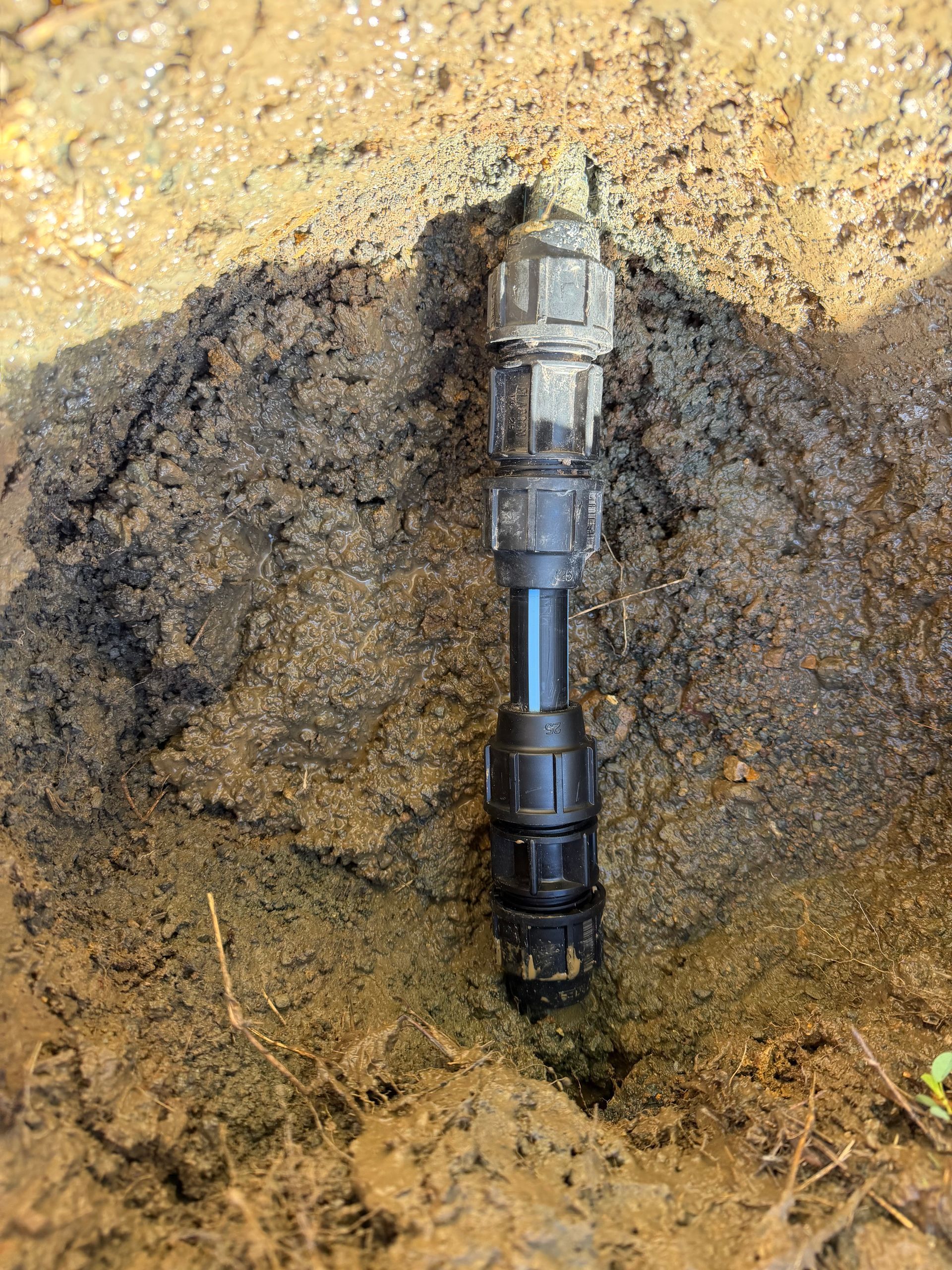 Irrigation pipe connector emerging from soil — Truflow Plumbing & Gas Solutions in Rockhampton City, QLD