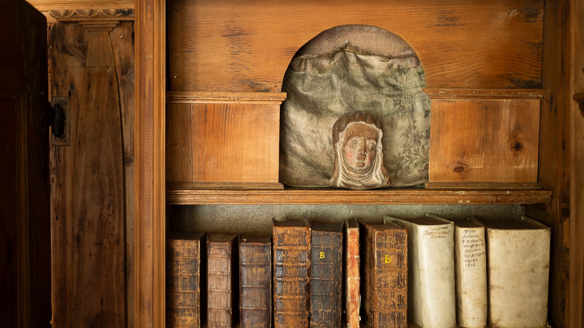 Historische Bücher und Figur in einem Holzschrank aus der Sammlung des Museums Ackerhus