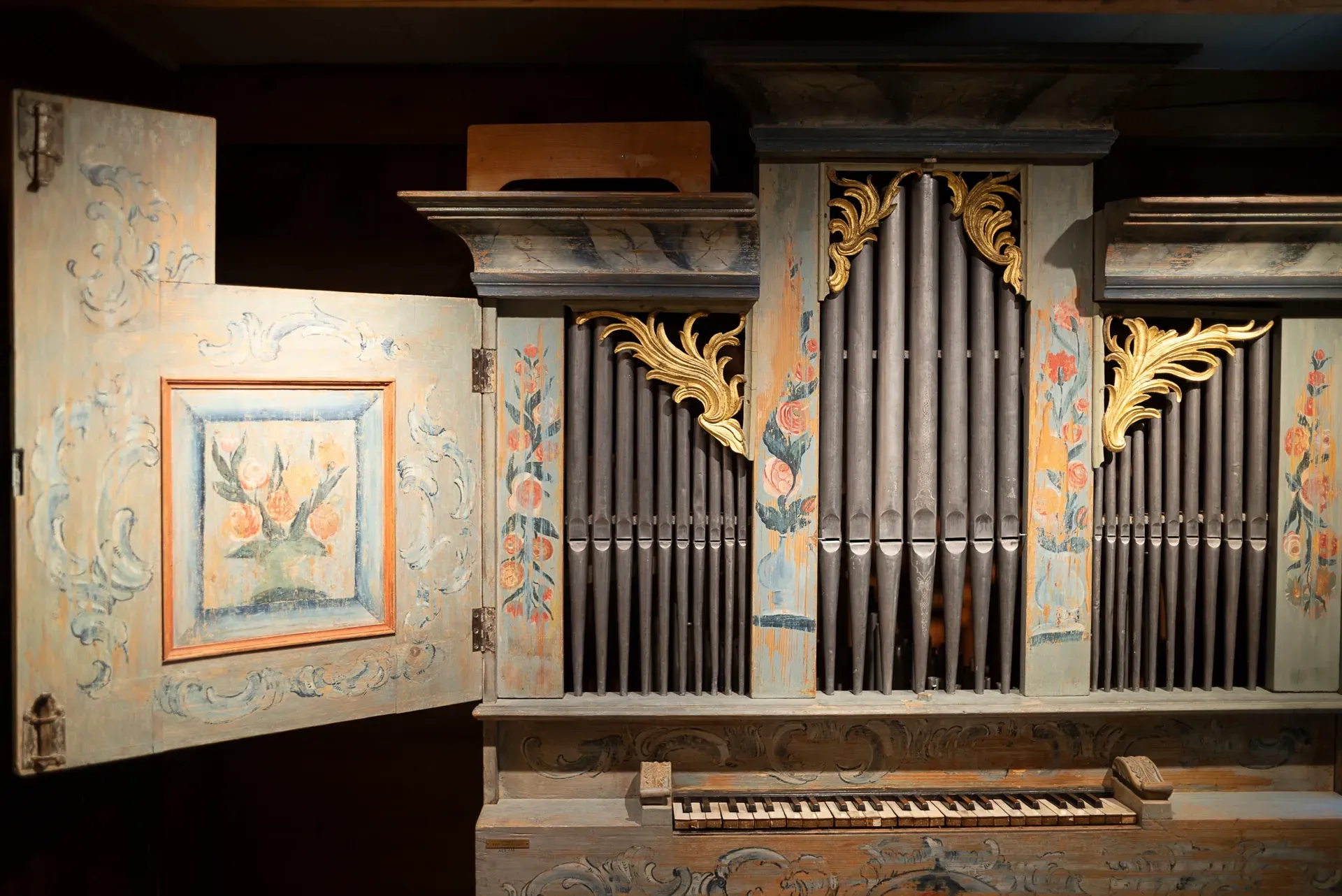 Antike Orgel im Ackerhus mit gemalten floralen Details und goldenen Akzenten, Tastatur sichtbar.