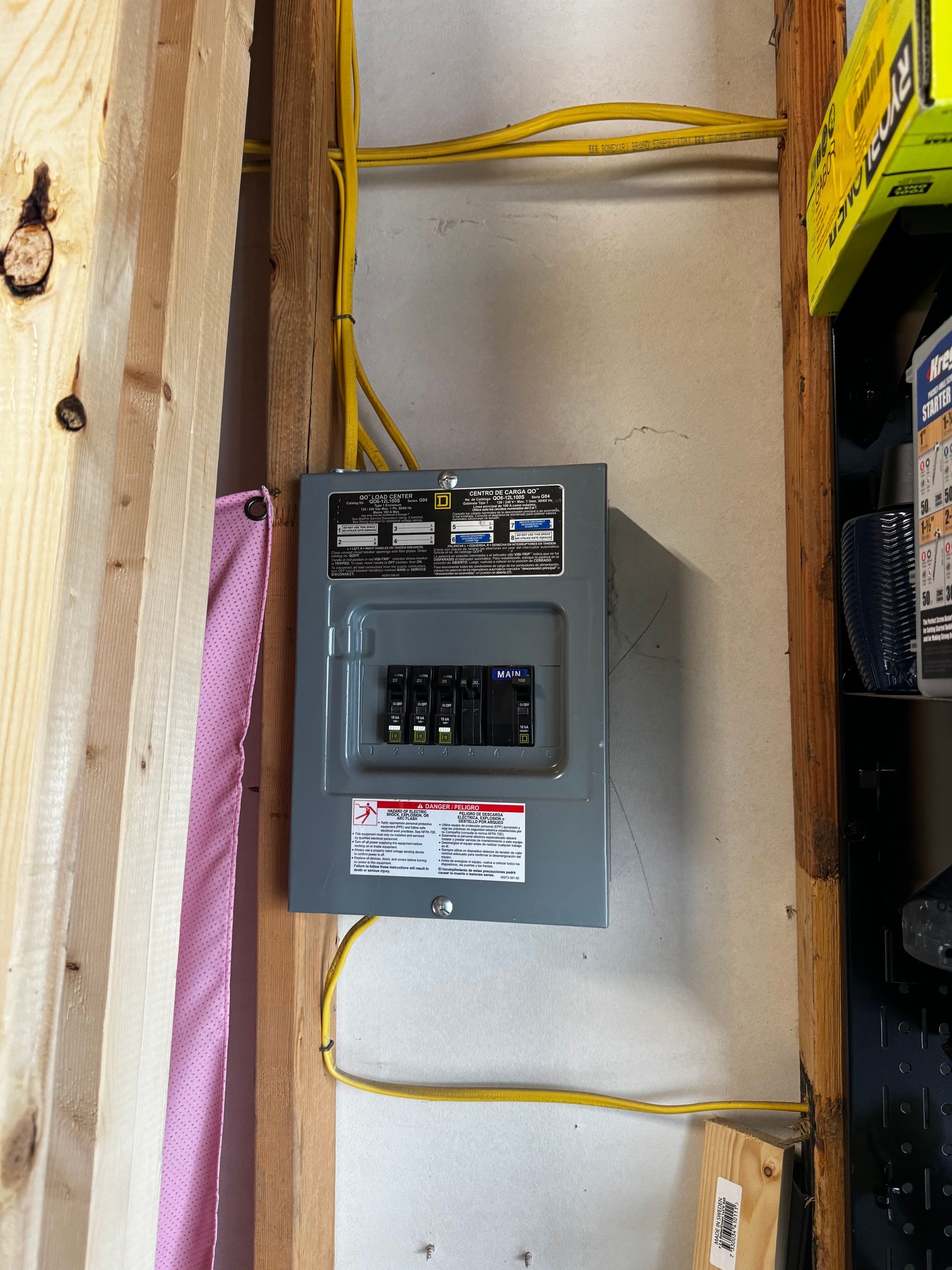 Electrician working on electrical wiring in a wall, wearing gloves and using a screwdriver.