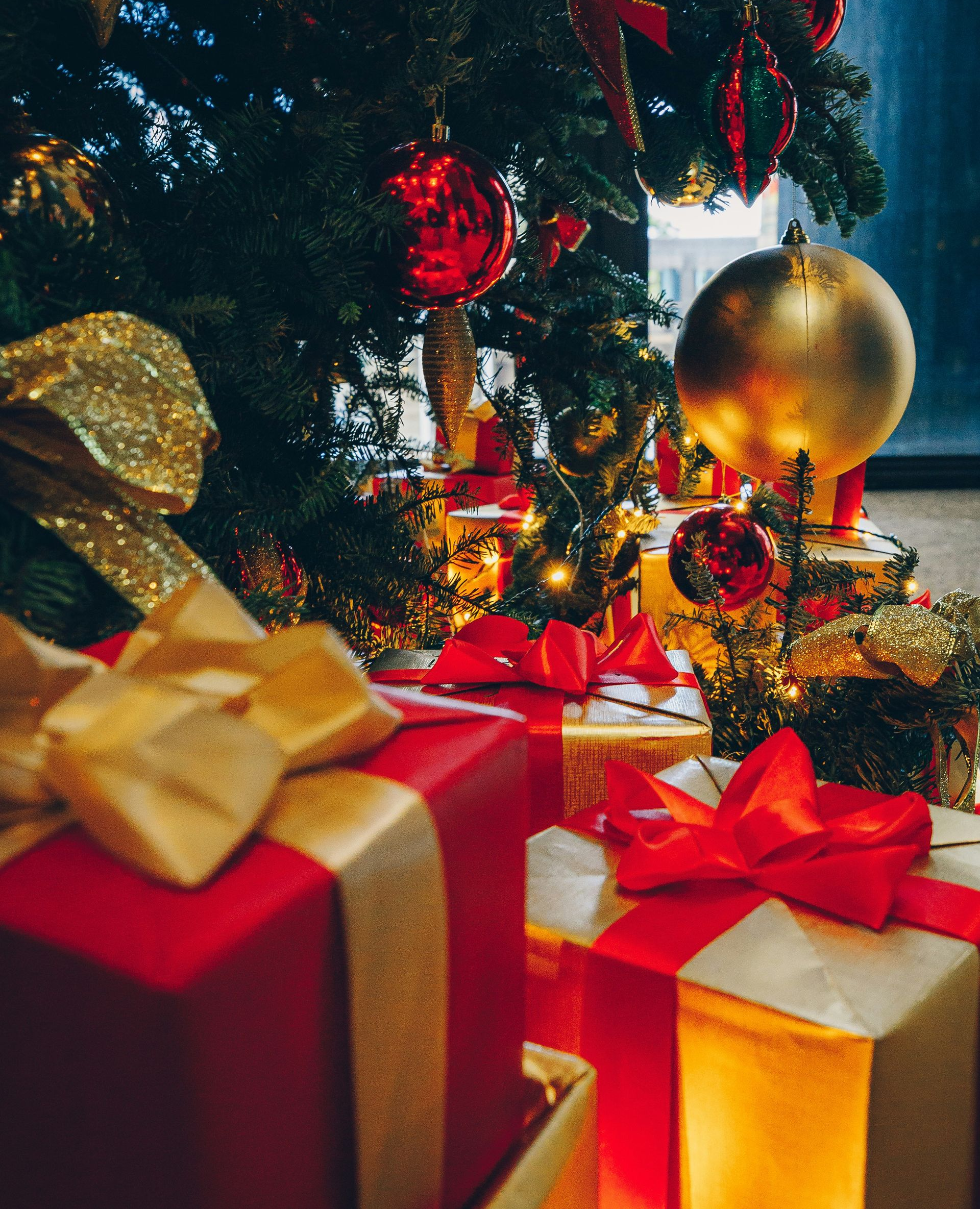 Christmas tree with red and gold ornaments and wrapped gifts beneath.