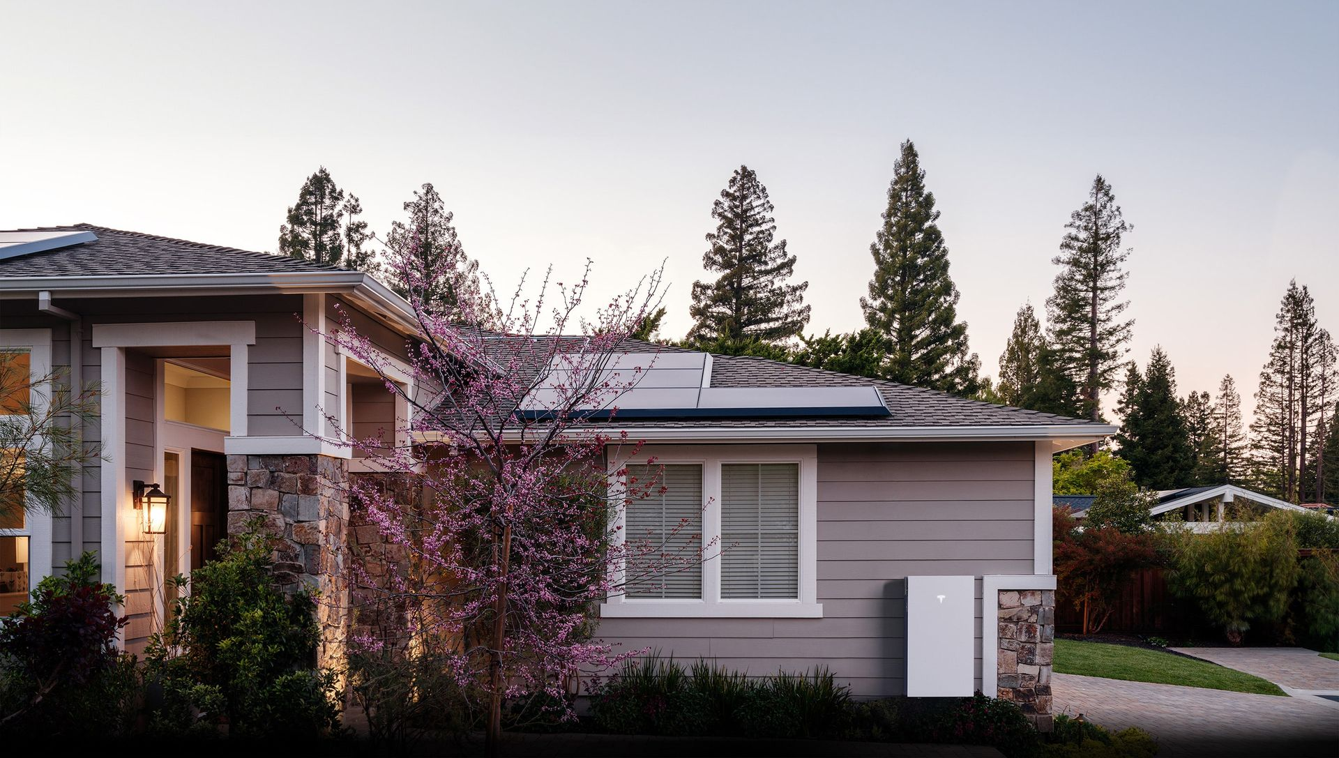 House with solar panels on the roof and a white energy storage unit outside.
