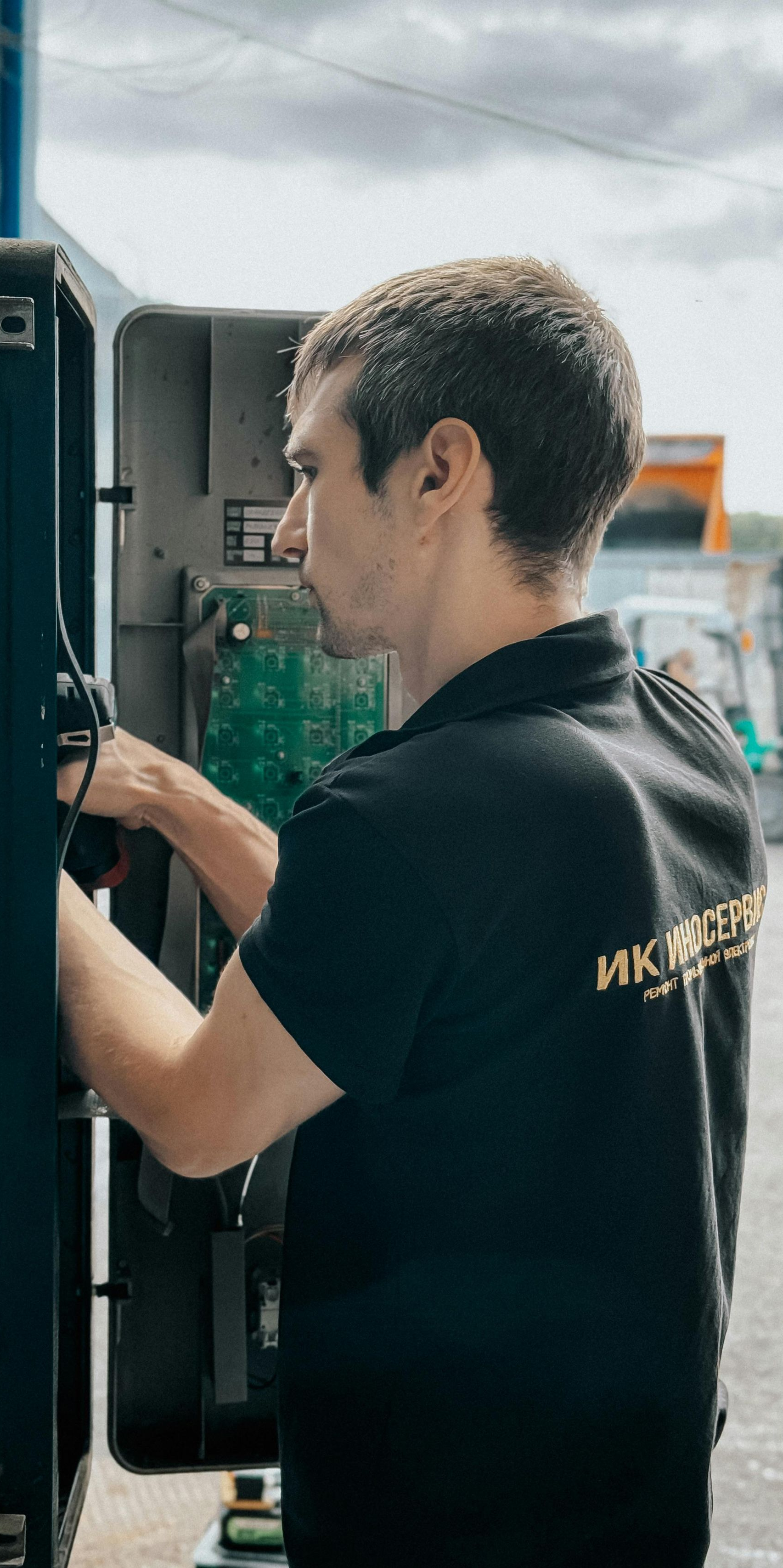 Man in black shirt repairing equipment outdoors.