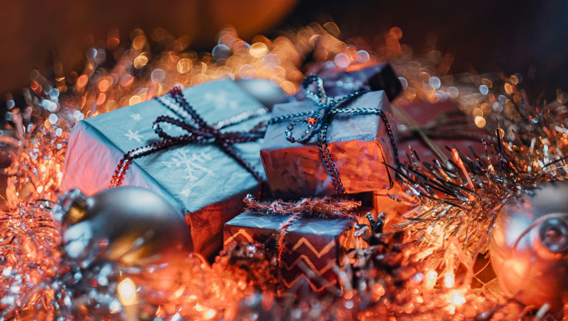 Wrapped gifts, ornaments, and tinsel with warm lighting, evoking a festive holiday scene.