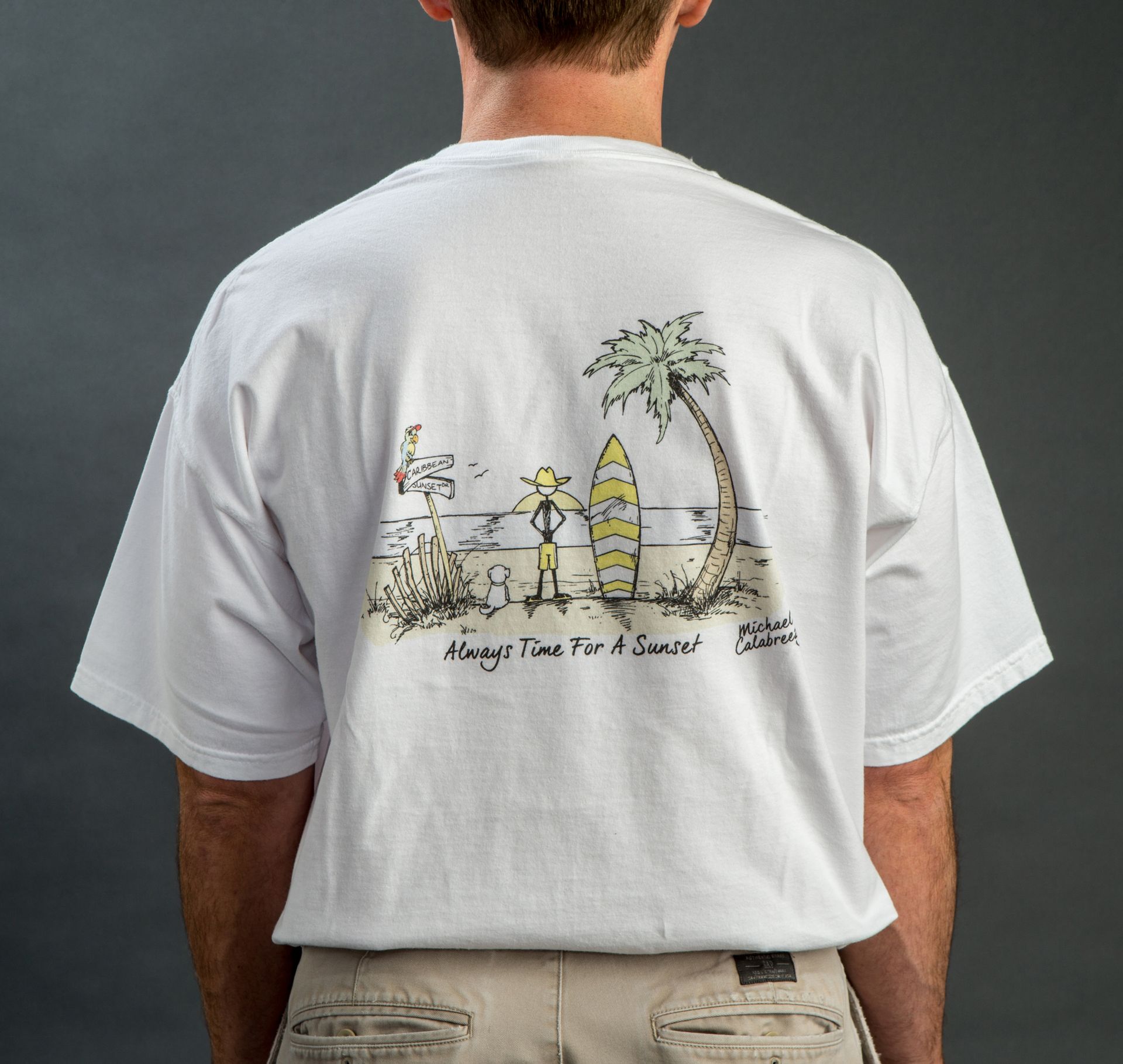 Man in white T-shirt viewed from behind, showing a small beach-themed graphic on the back