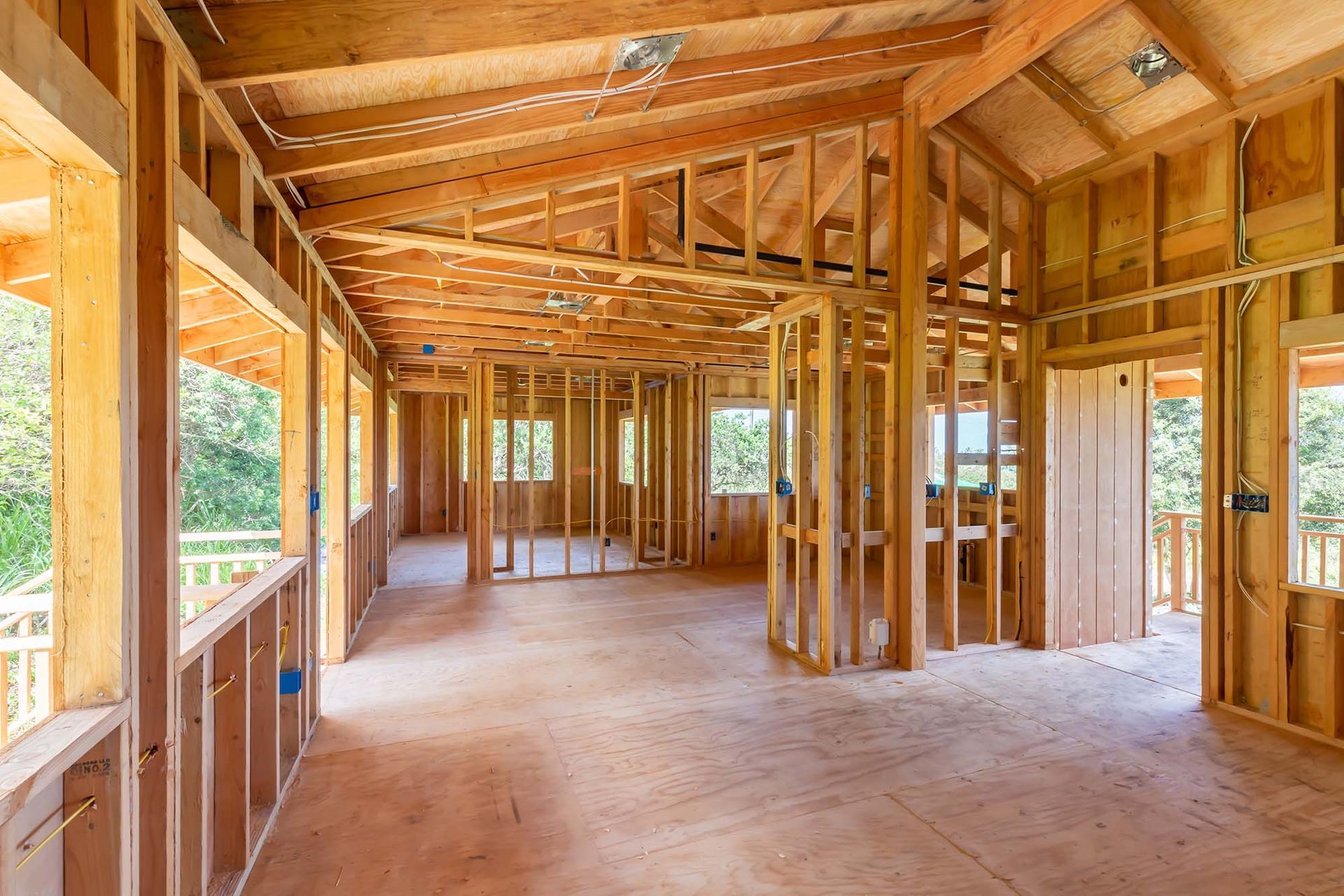 Unfinished wooden house interior with exposed framing, beams, and subflooring under construction