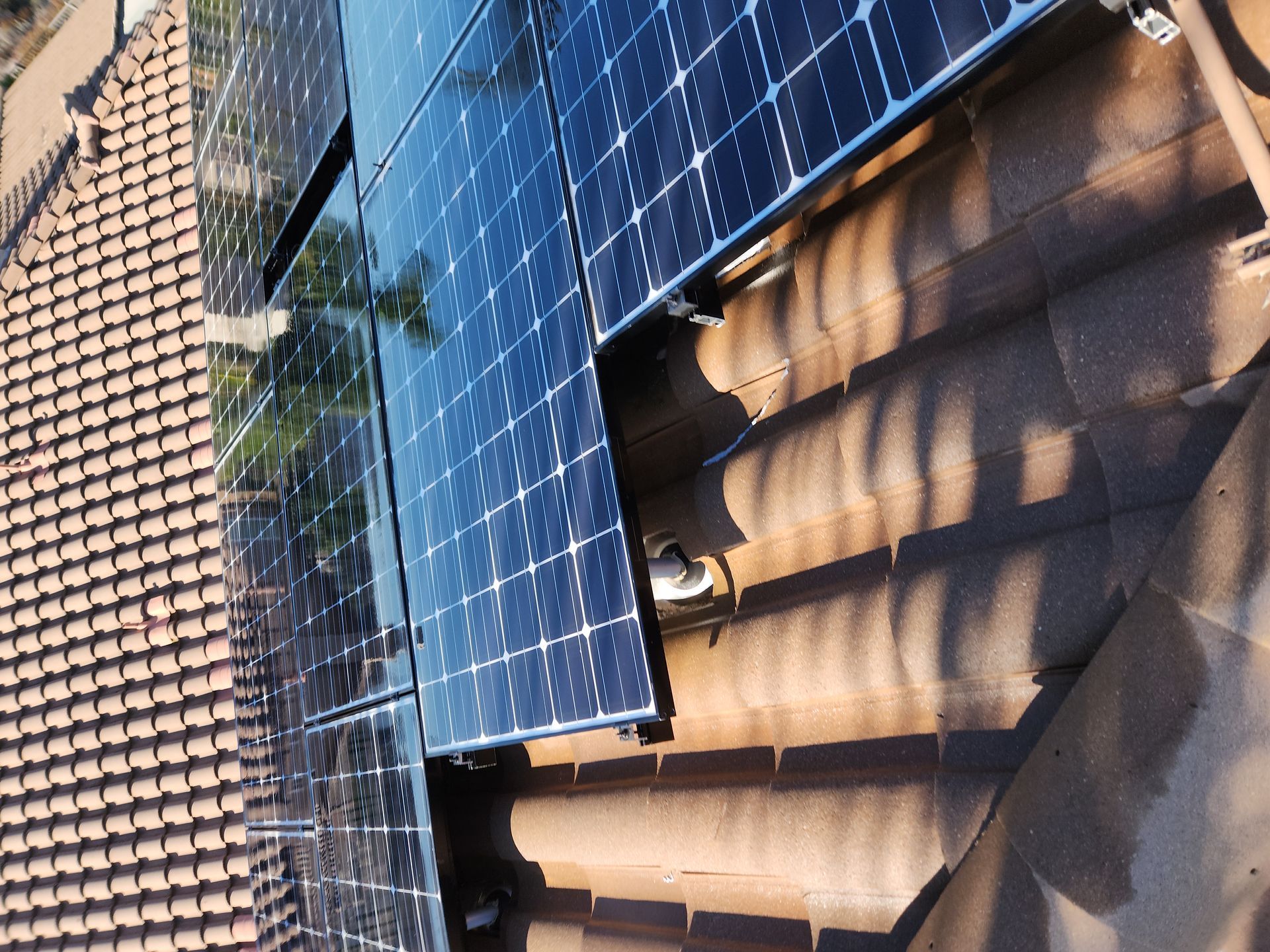 Solar panels mounted on a tiled roof, viewed close up from above.