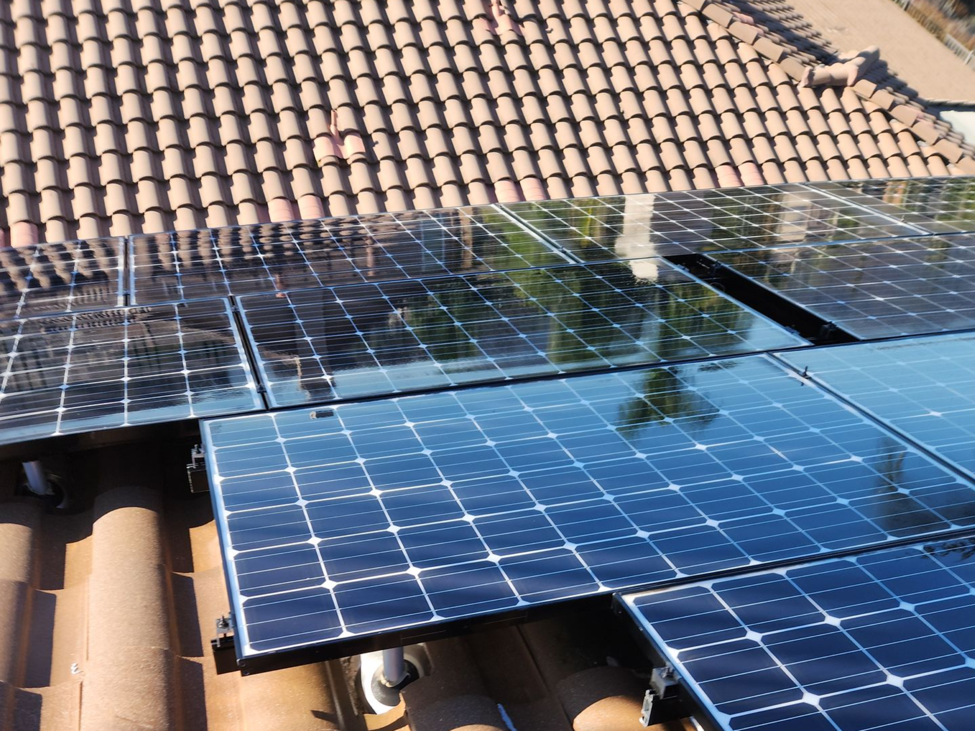 Solar panels mounted on a tiled roof under bright sunlight