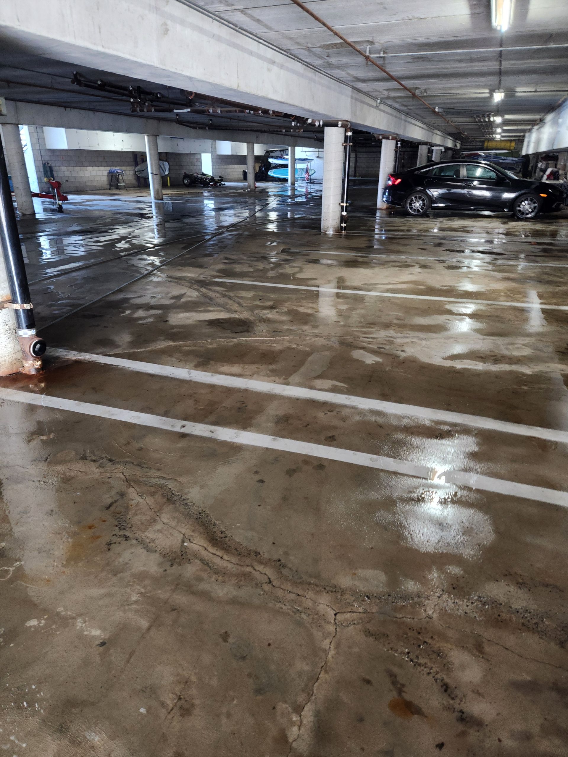 Wet concrete parking garage with parked cars and reflective floor markings