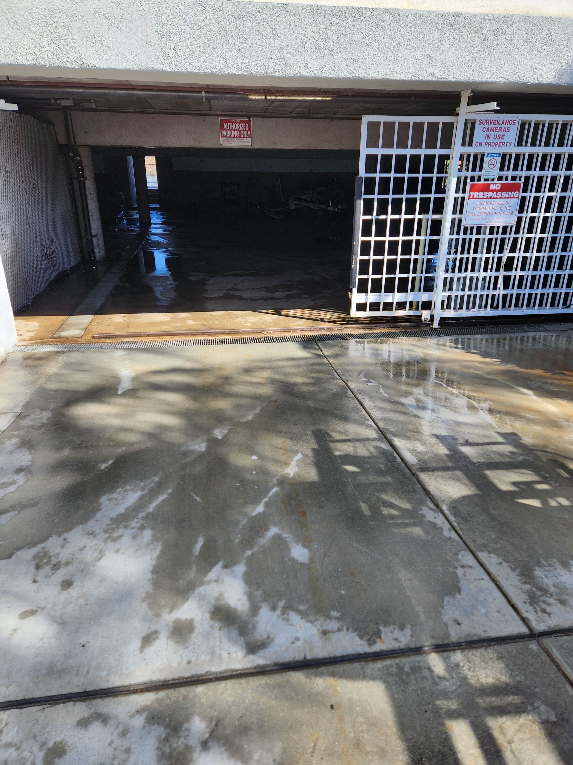 Concrete parking garage entrance with open gate and wet floor