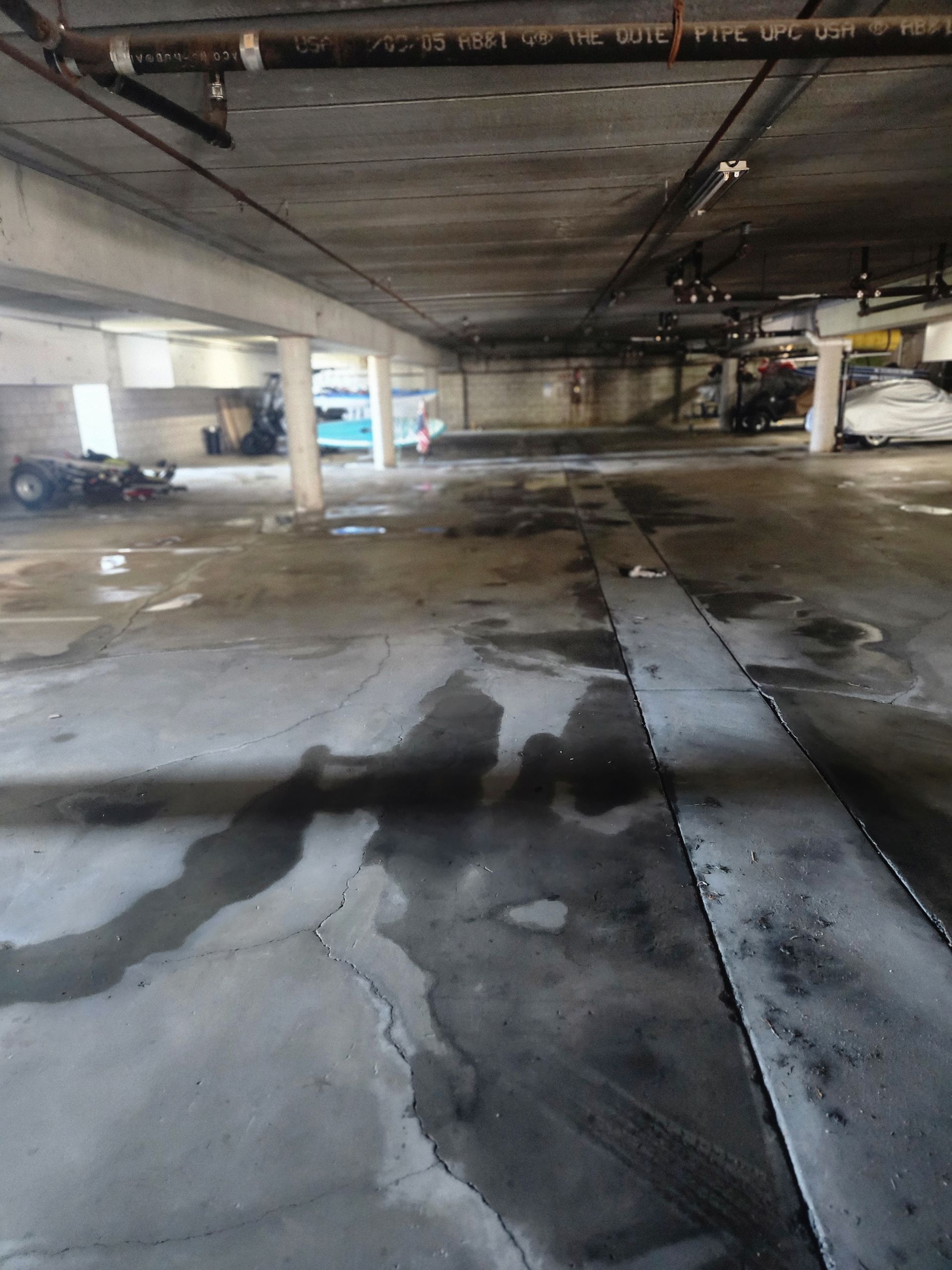 Empty concrete parking garage with wet floor and support columns