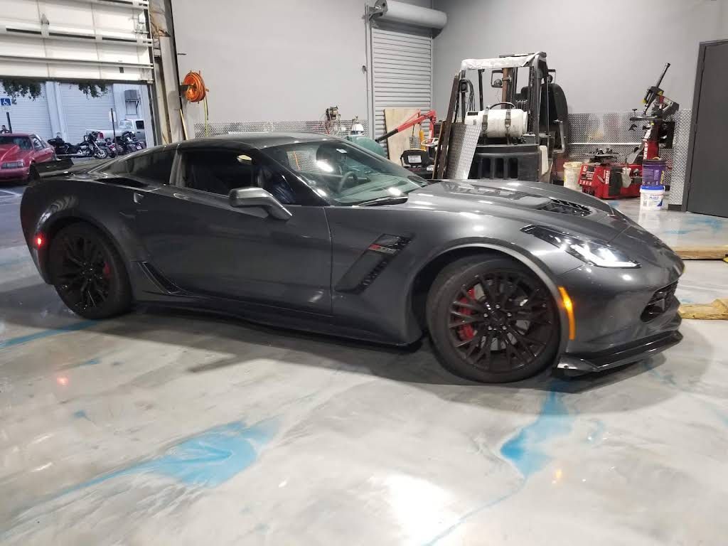 A grey Chevrolet Corvette Z06 parked on a light-colored, glossy epoxy floor inside a garage.