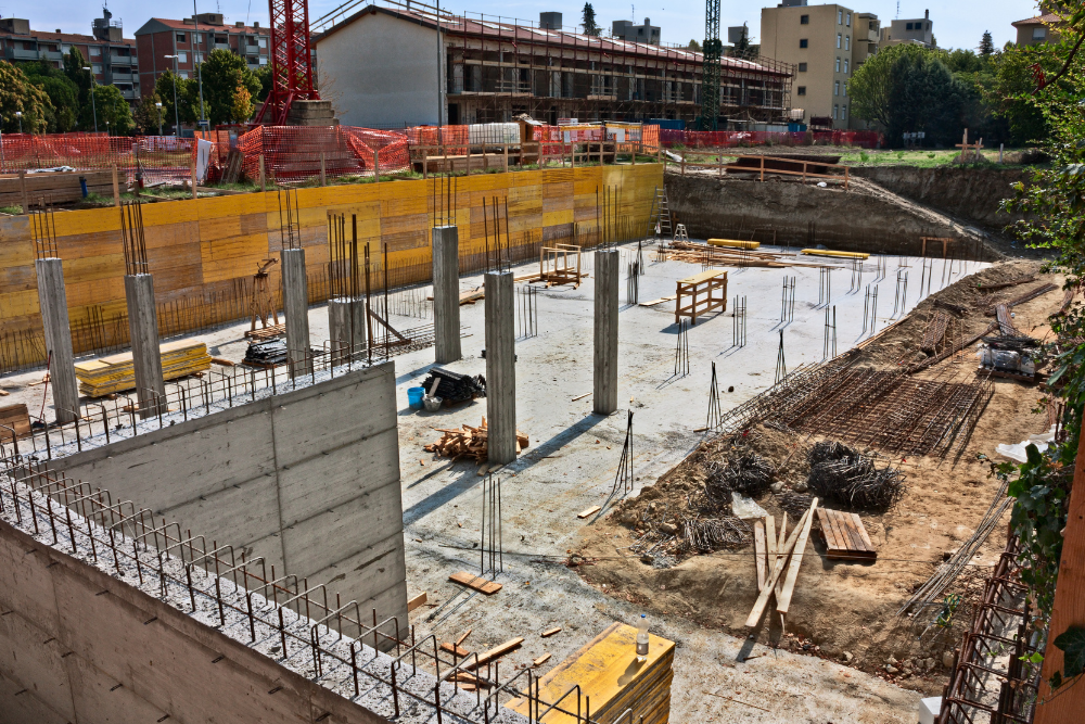 A construction site with a lot of concrete pillars and a building in the background.
