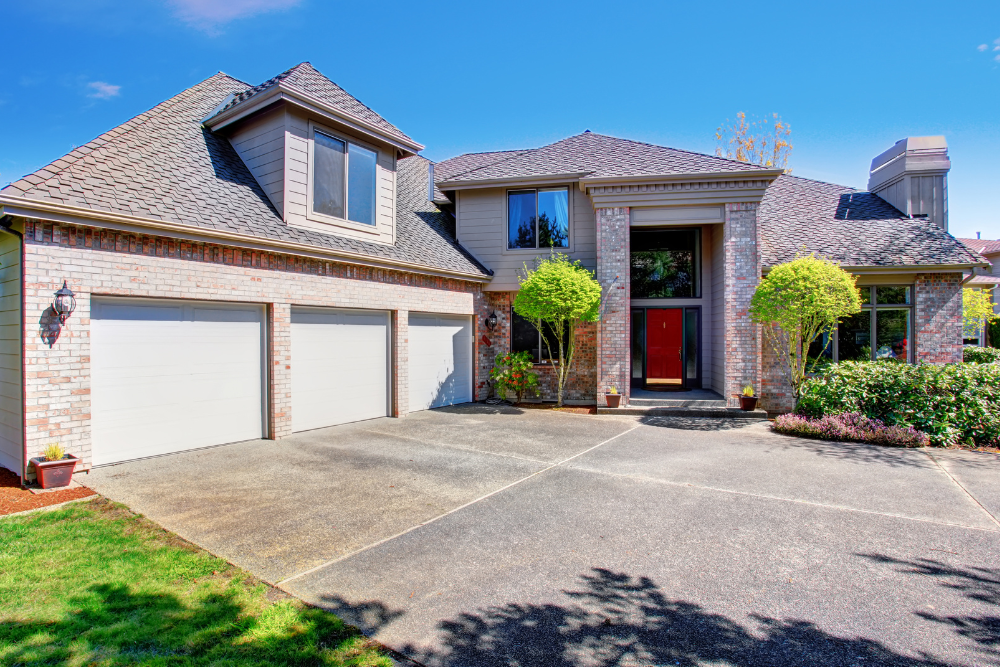 A large brick house with two garage doors and a large driveway.