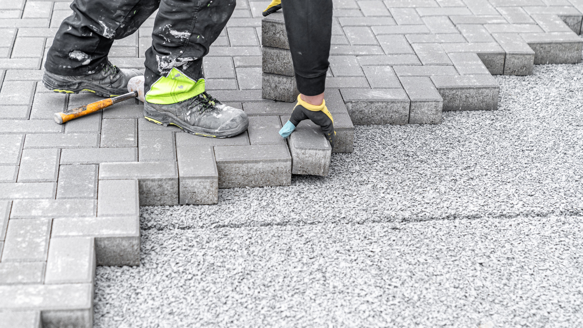 A man is laying bricks on a sidewalk.