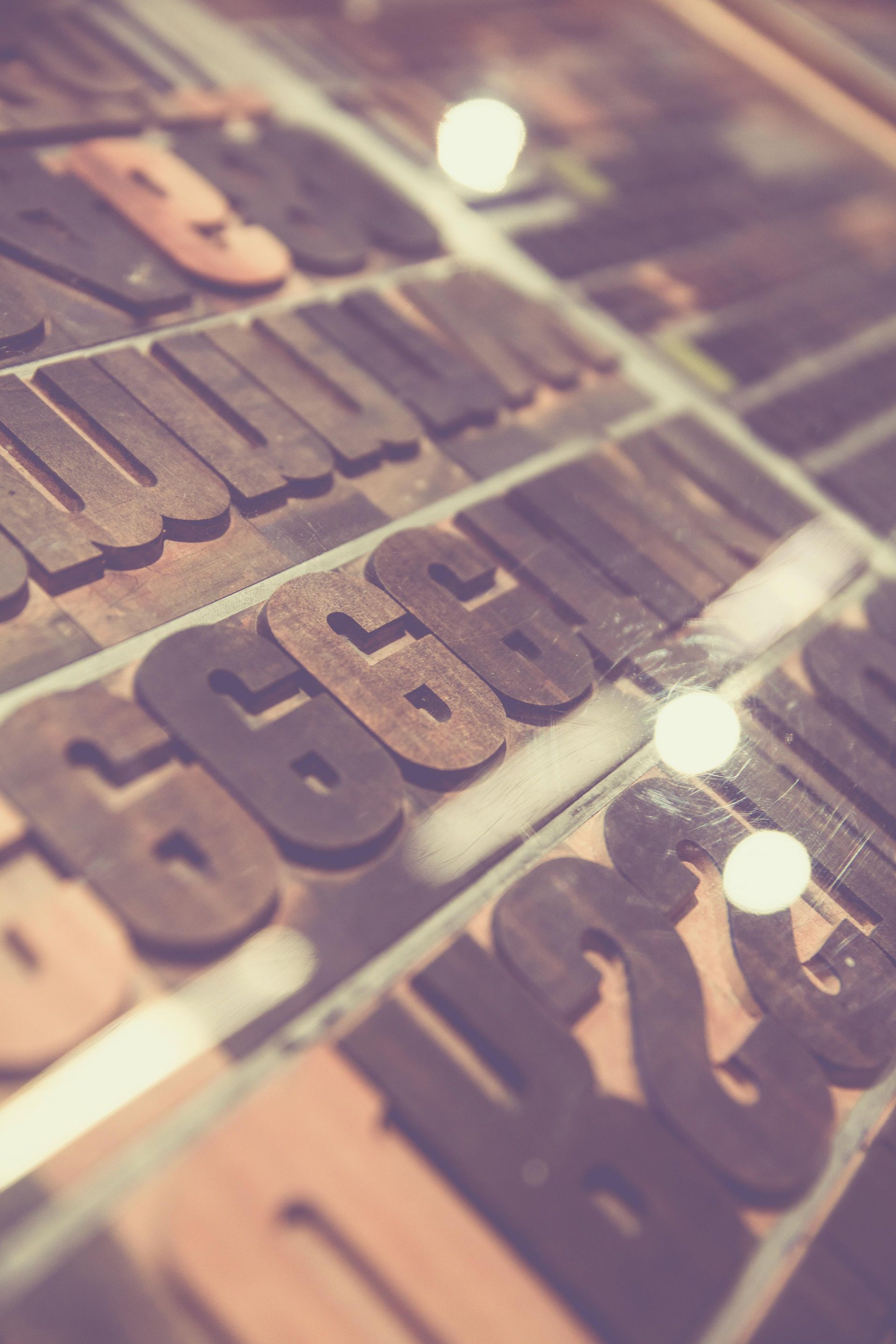 Wooden printing press type arranged in a tray, including numbers and letters.